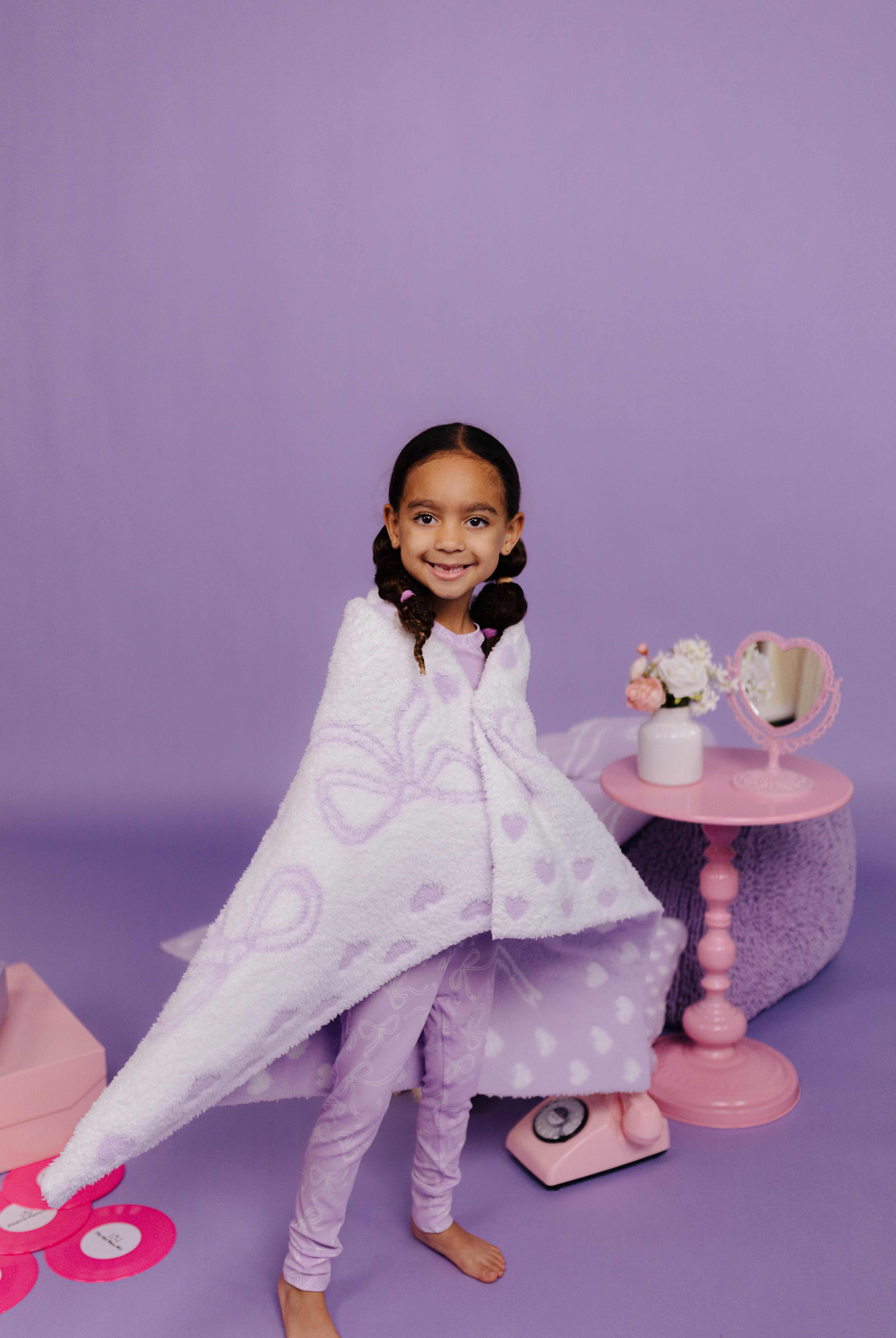 child wrapped in purple and white bow blanket