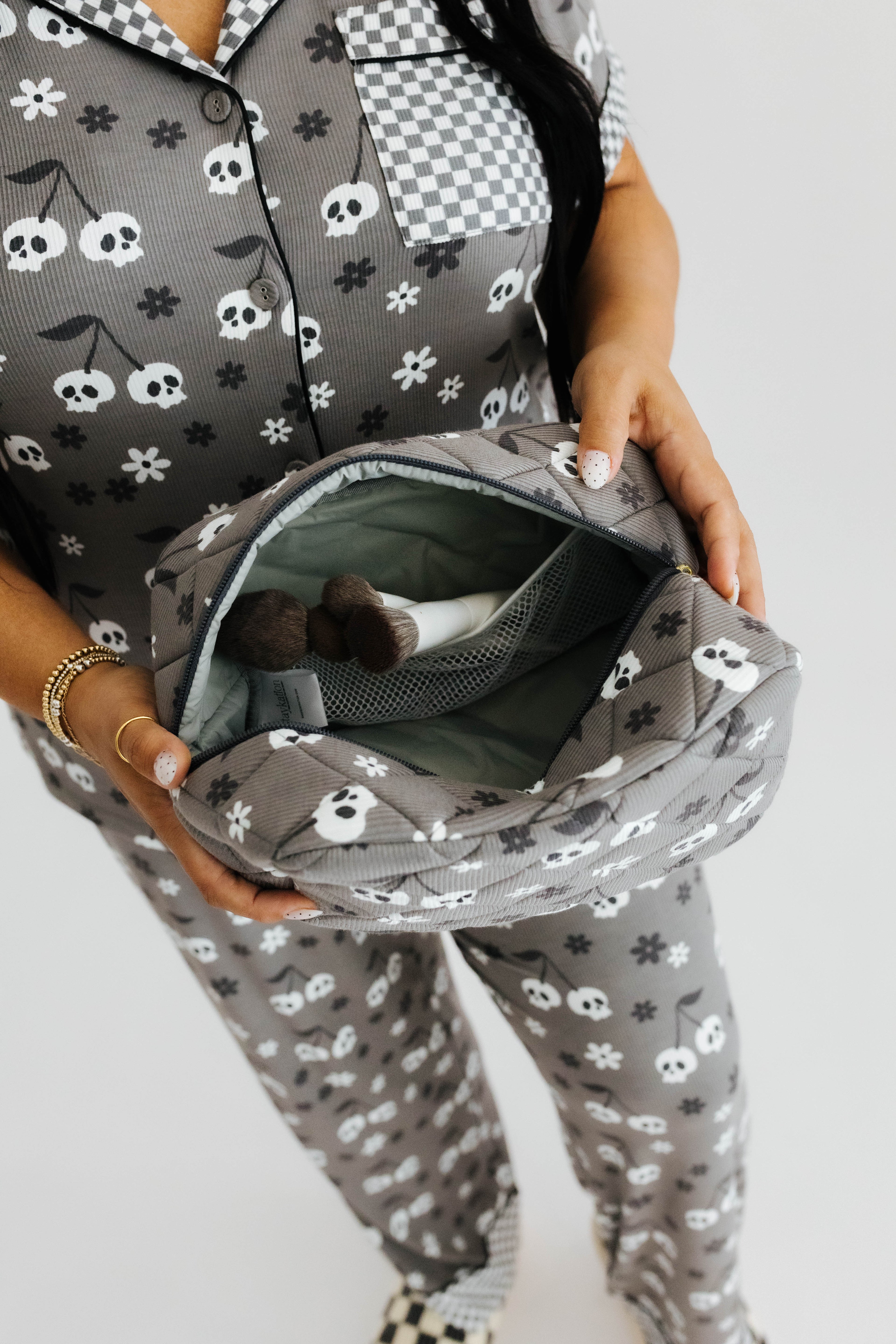 model holding skelly cosmetic bag opened showing the space of it and makeup brushes inside