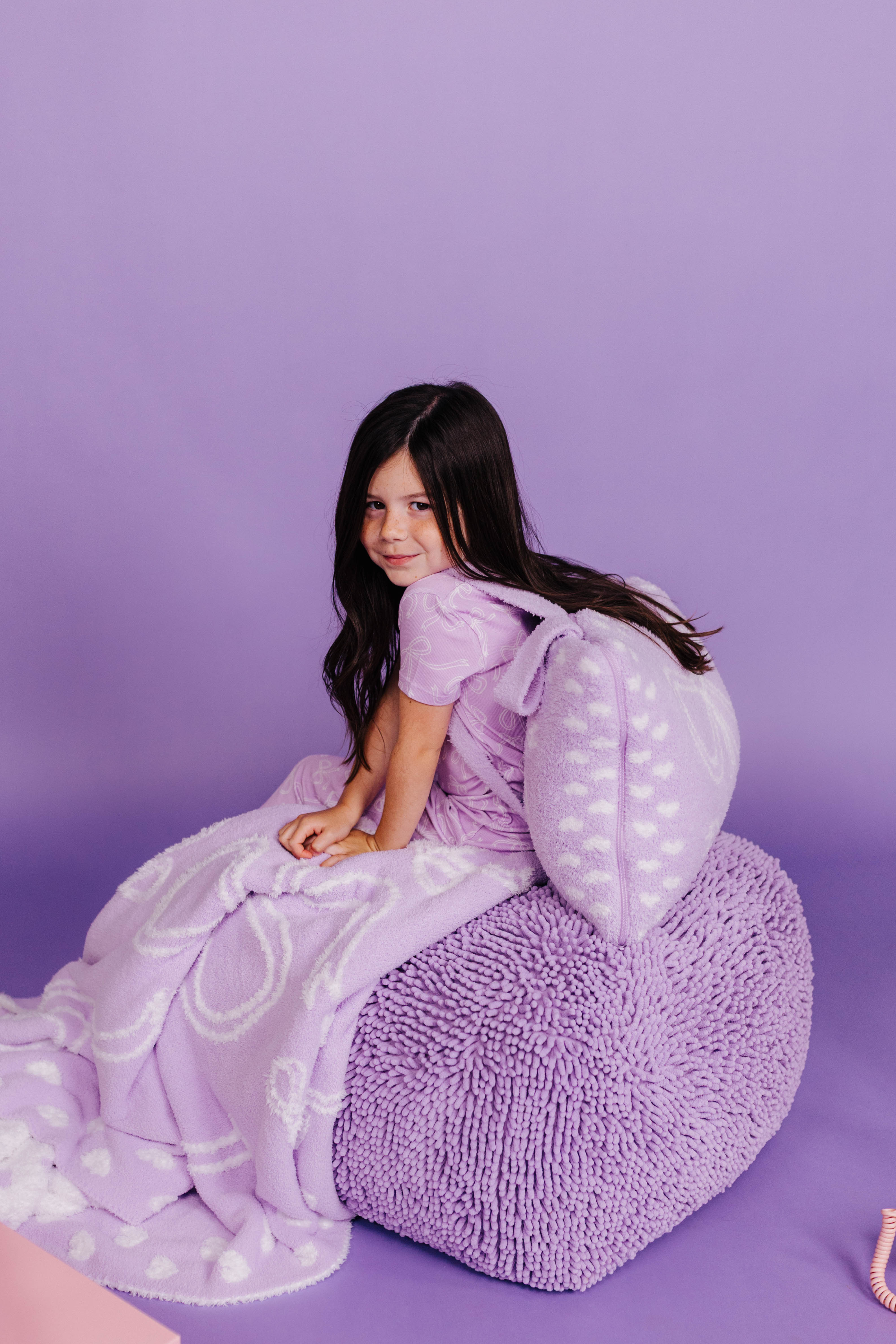 young girl with purple quillow being worn on her back