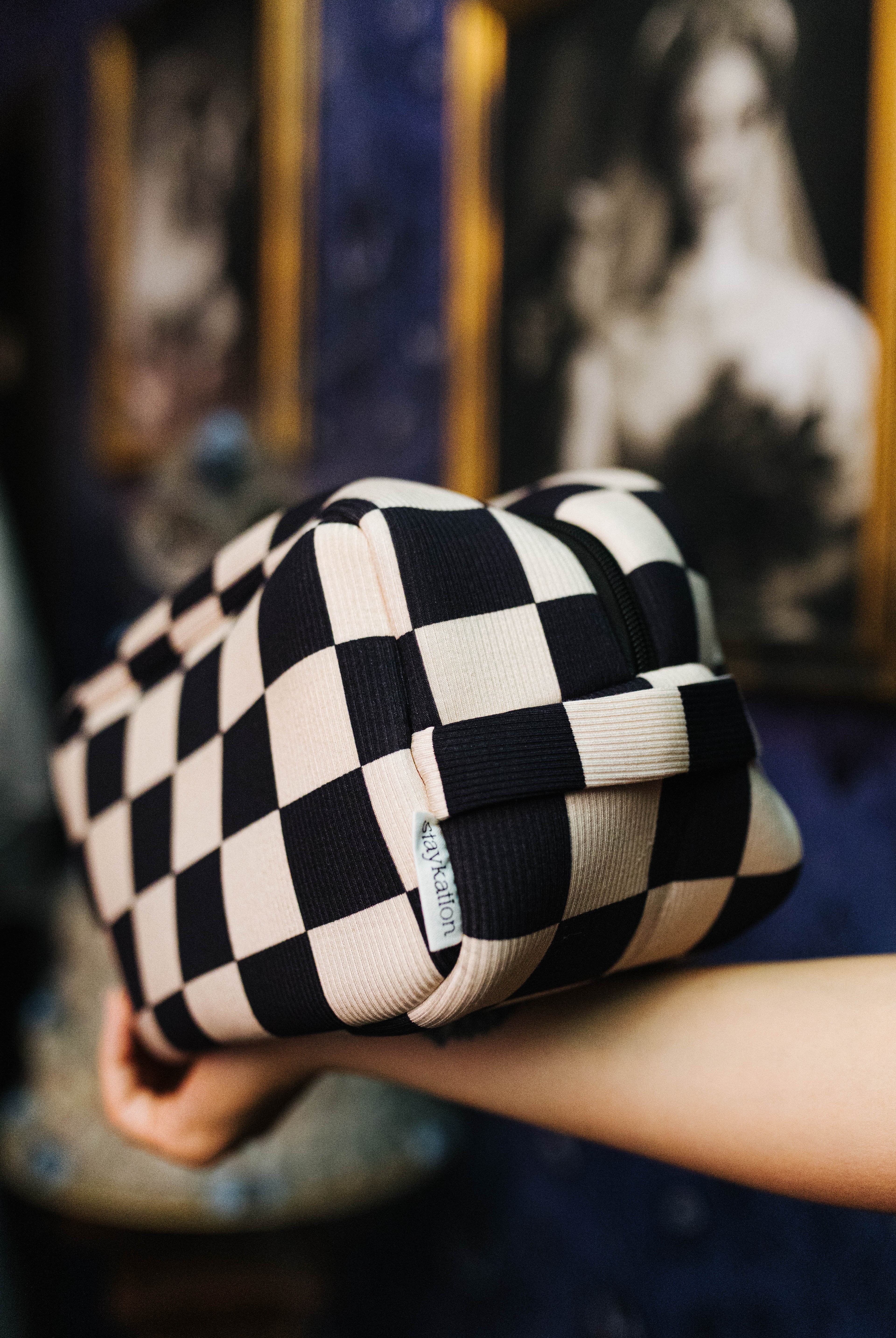 Side view of the sand and black check cosmetic bag