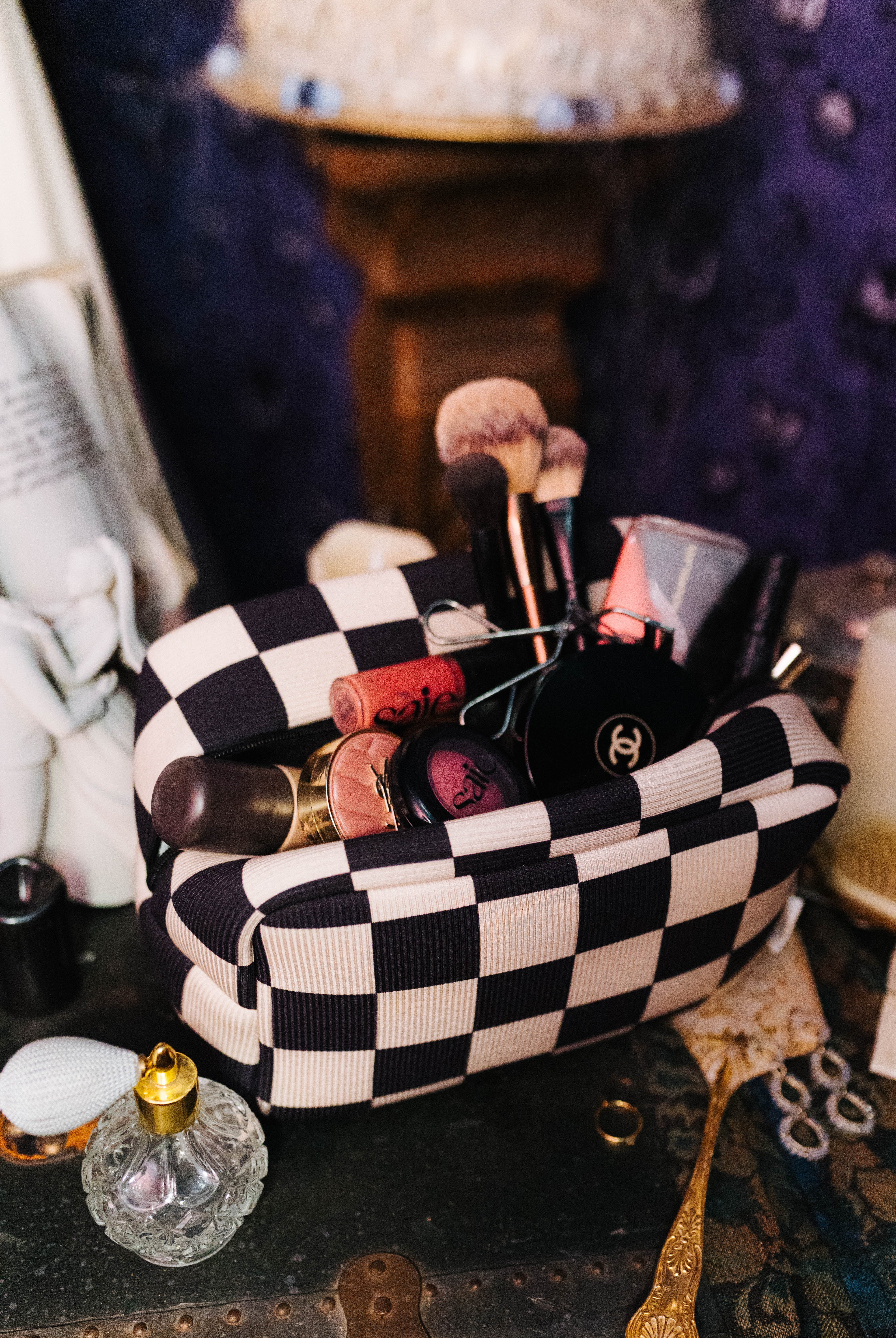 Open sand and black check cosmetic bag filled with makeup
