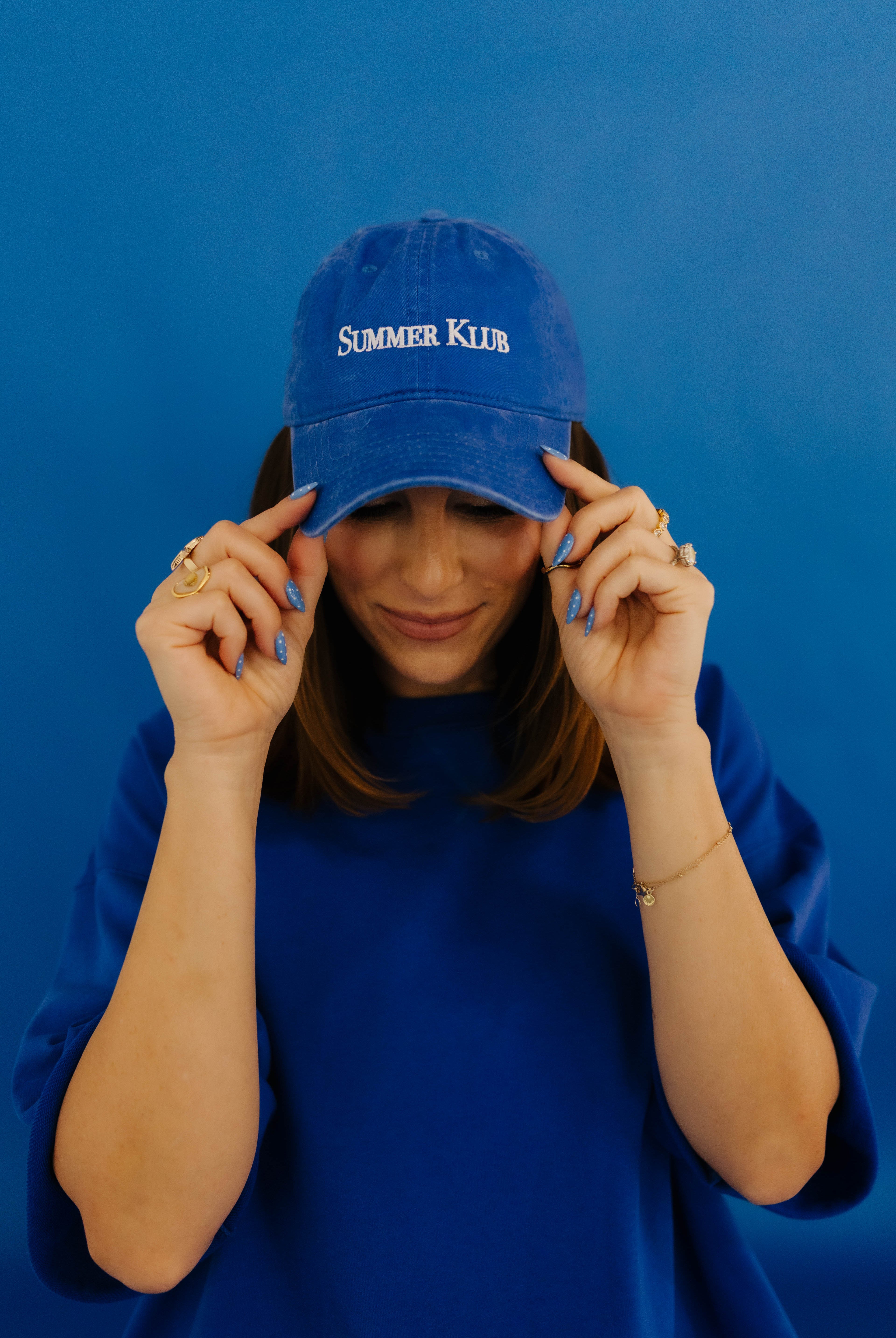 Person wearing a blue cap with 'Summer Klub' text against a blue background