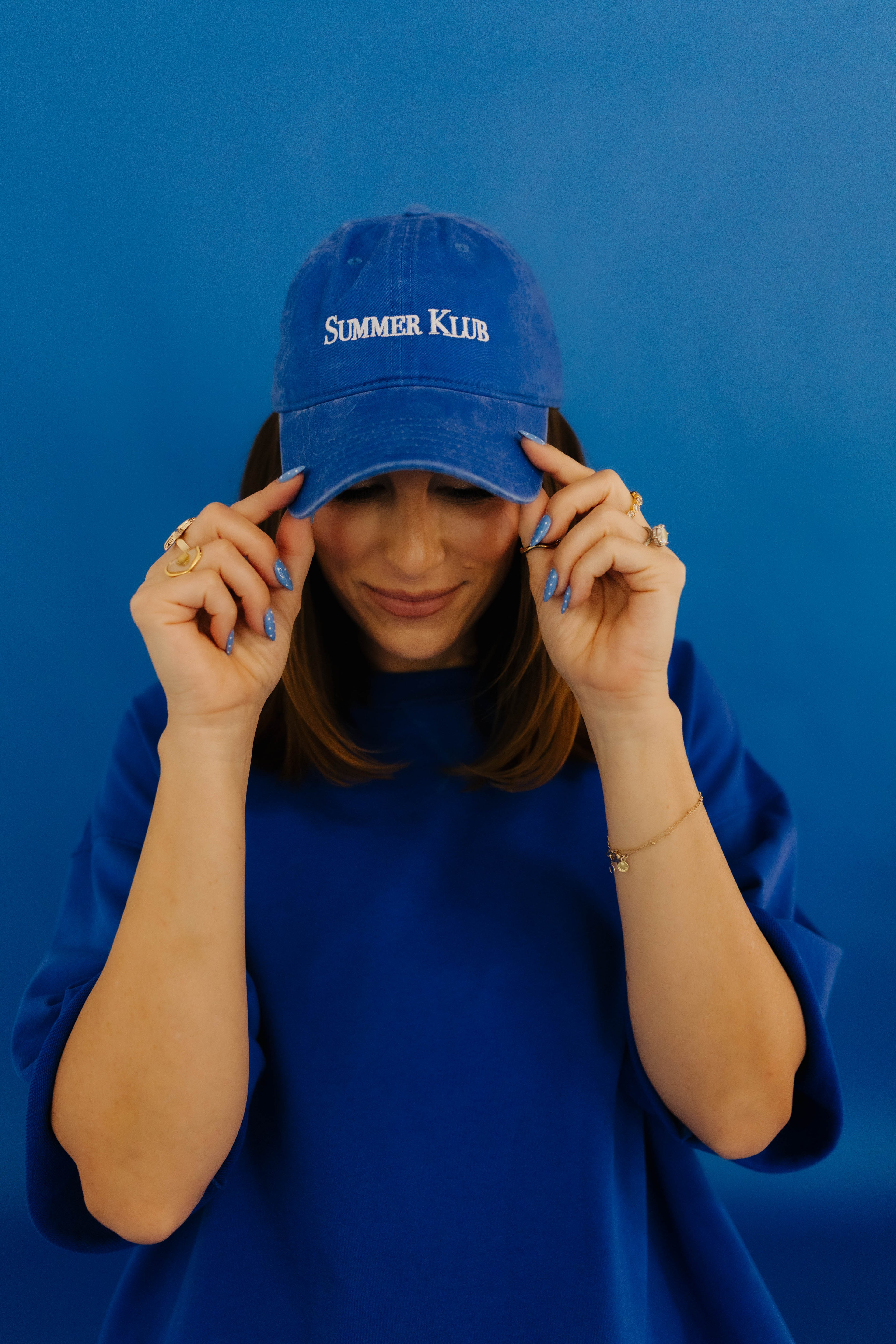 Person wearing a blue cap with 'Summer Klub' text against a blue background