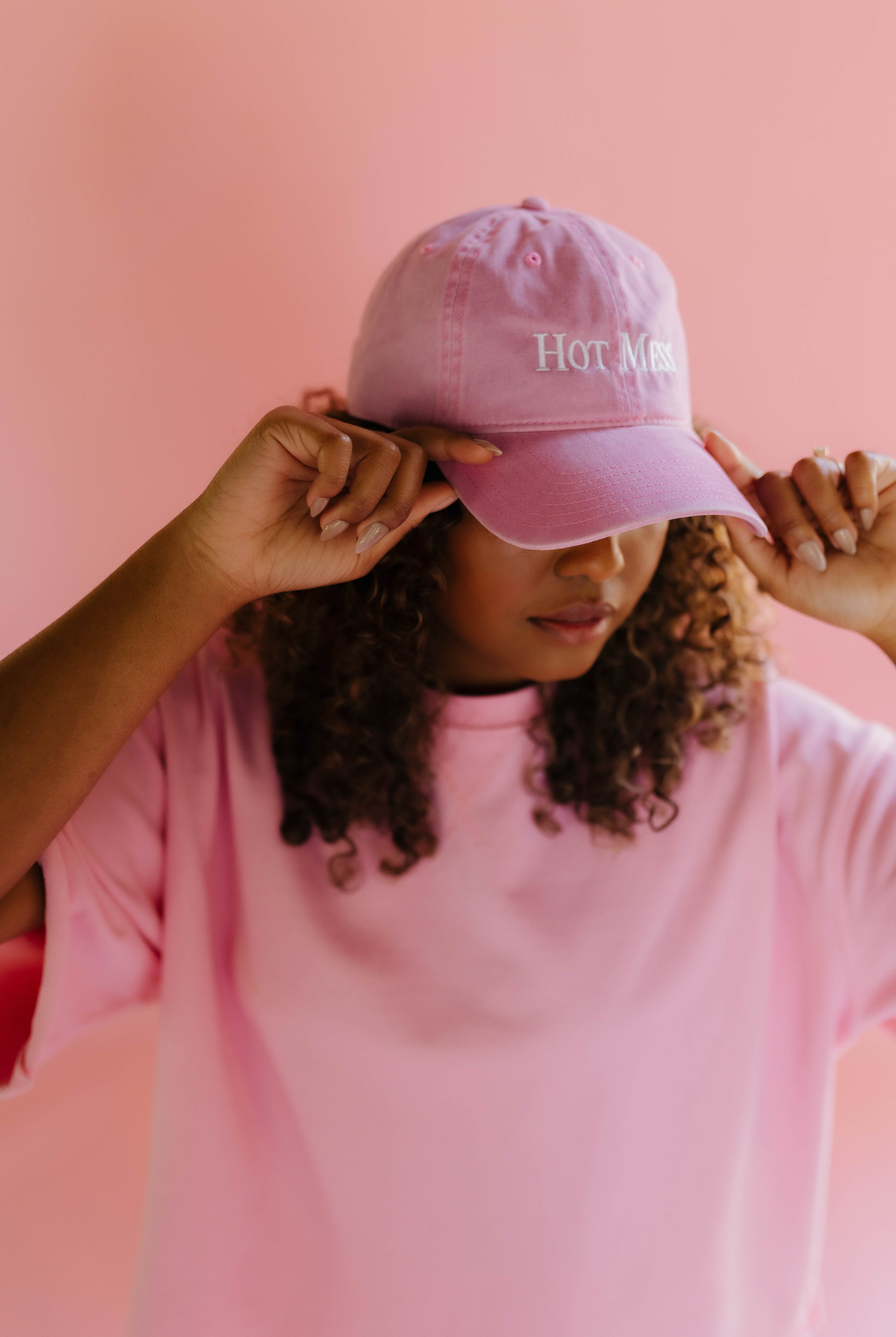 Person wearing a pink hat with hot mess written on it