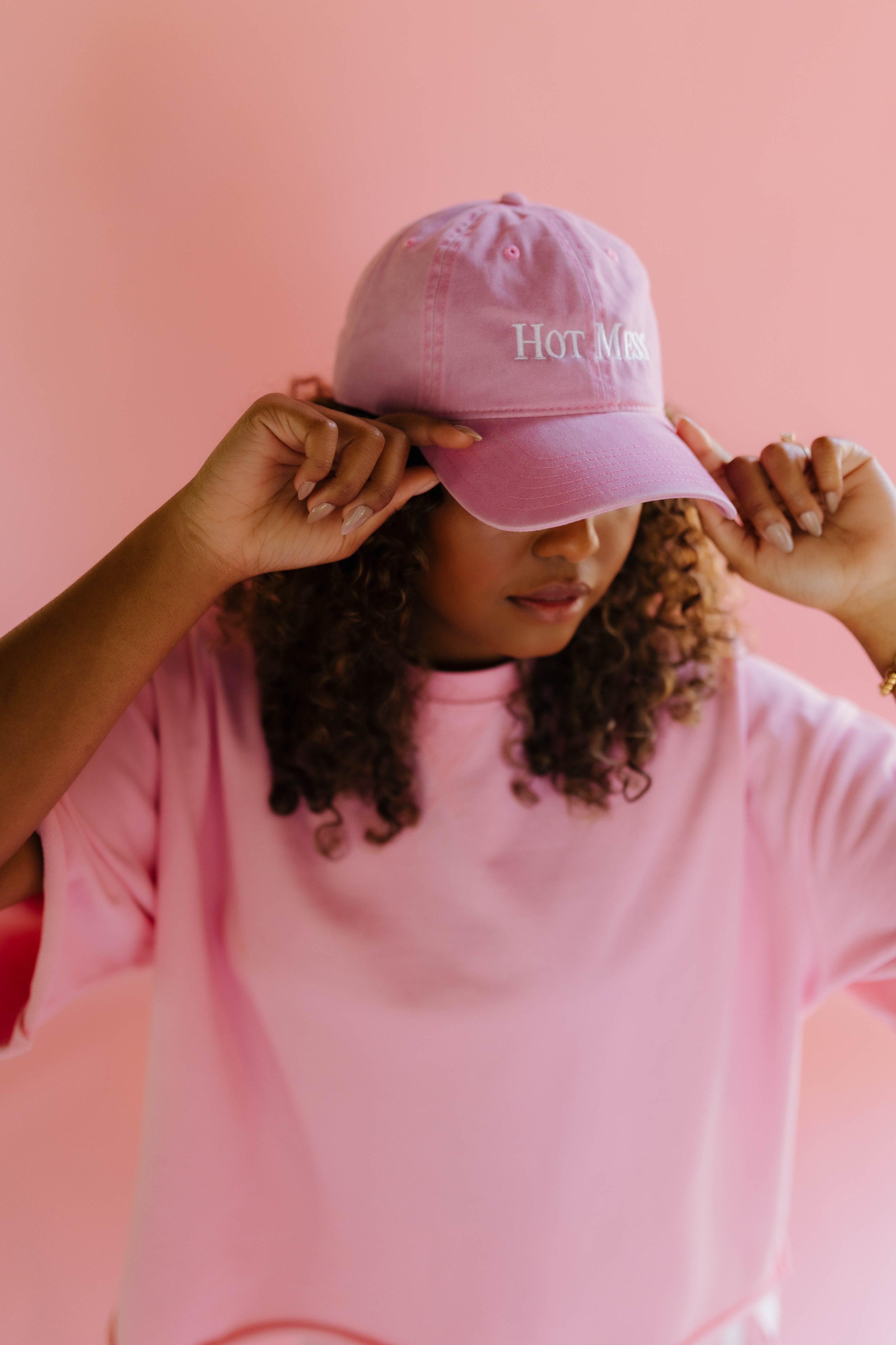 Person wearing a pink hat with hot mess written on it