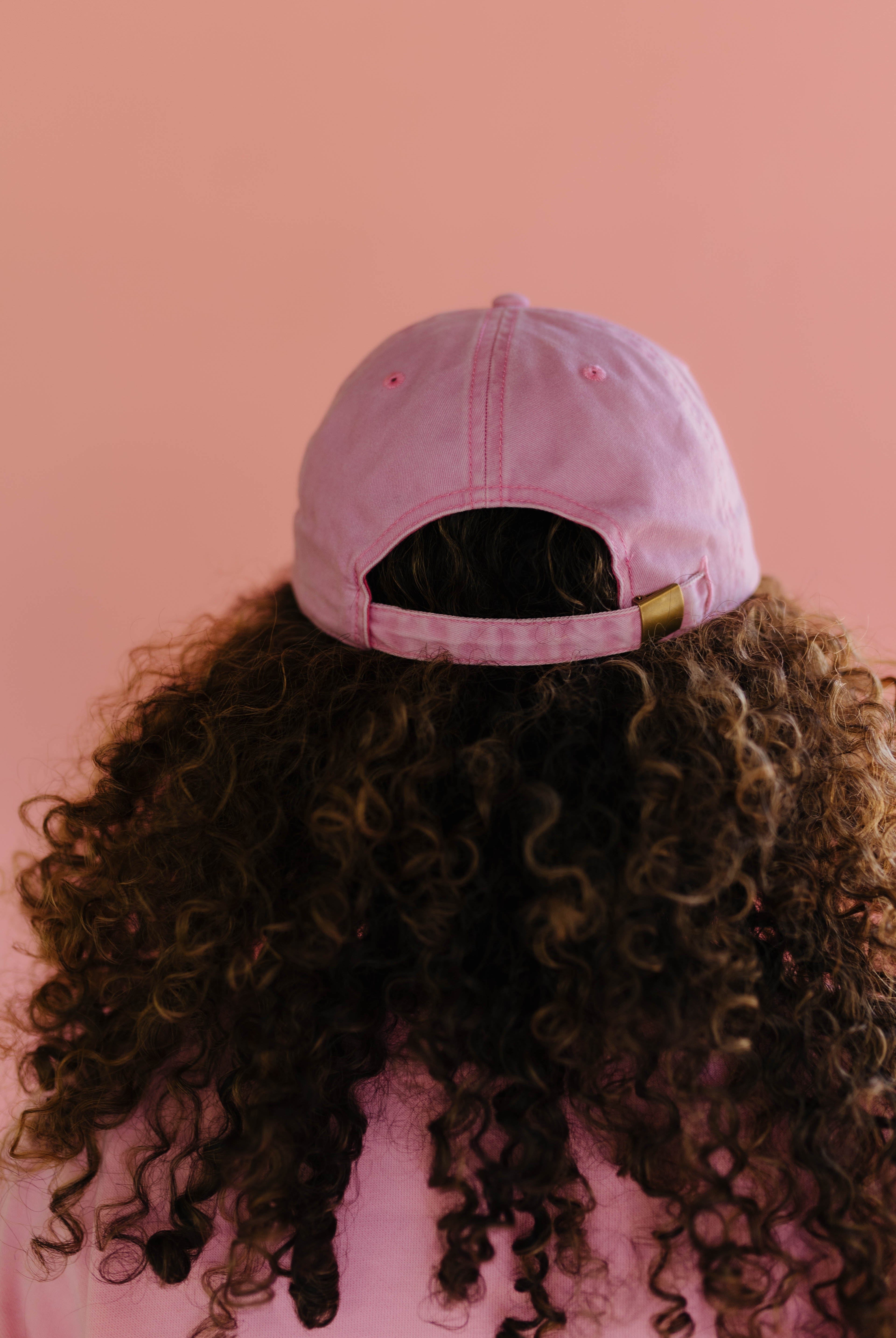 Person wearing a pink hat with a pink background