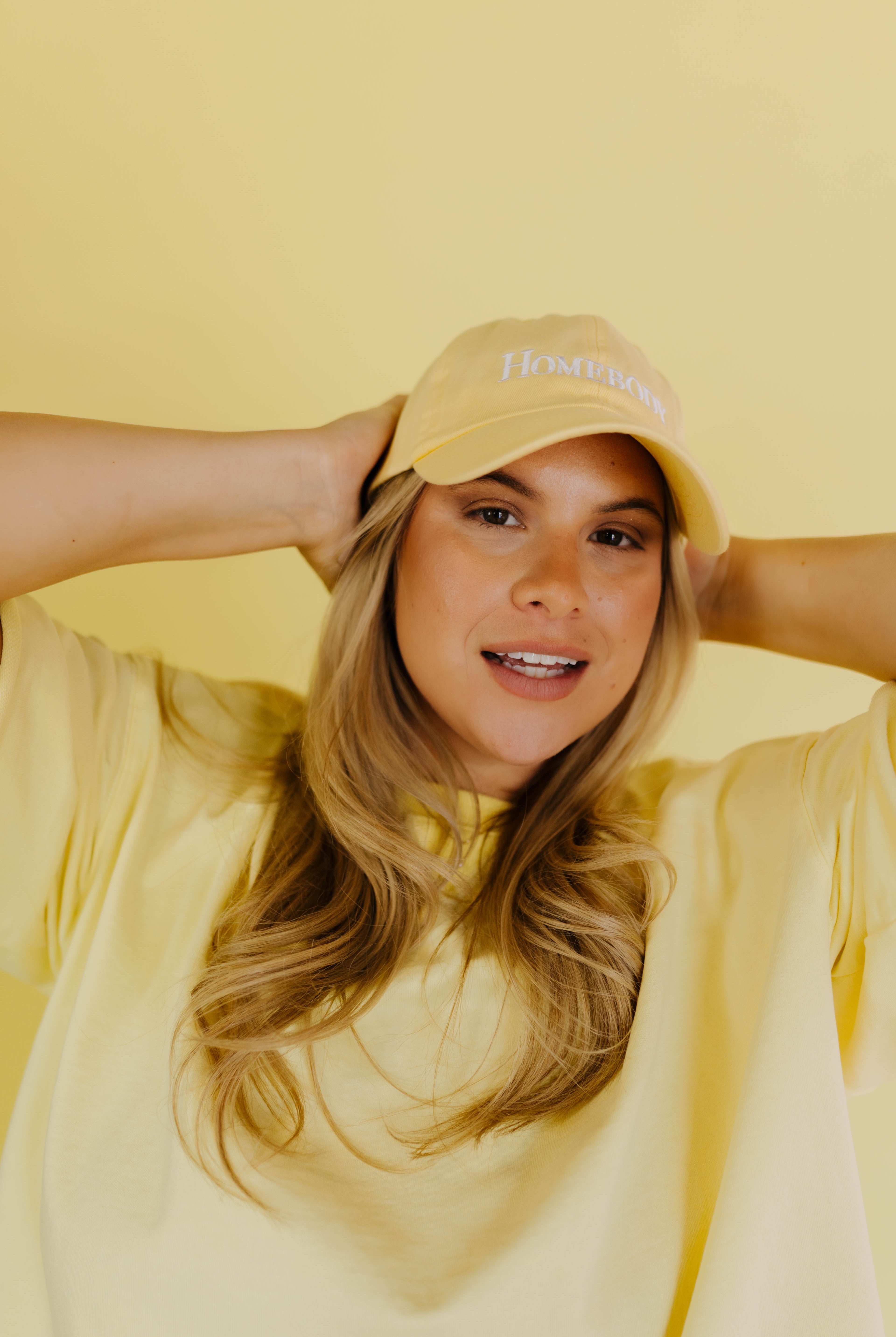 Woman wearing a yellow hat and shirt against a yellow background