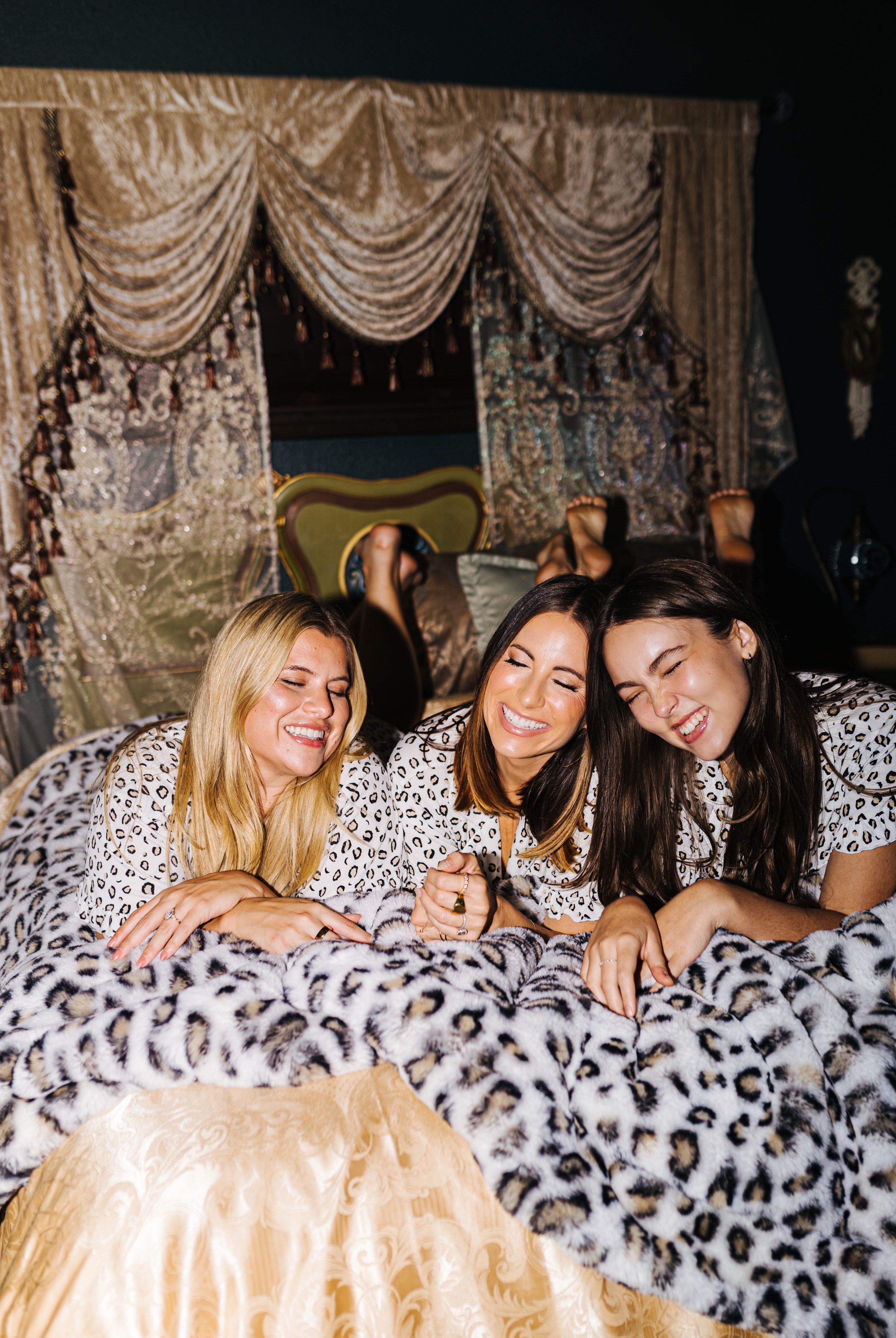 Three models sharing a leopard faux fur blanket
