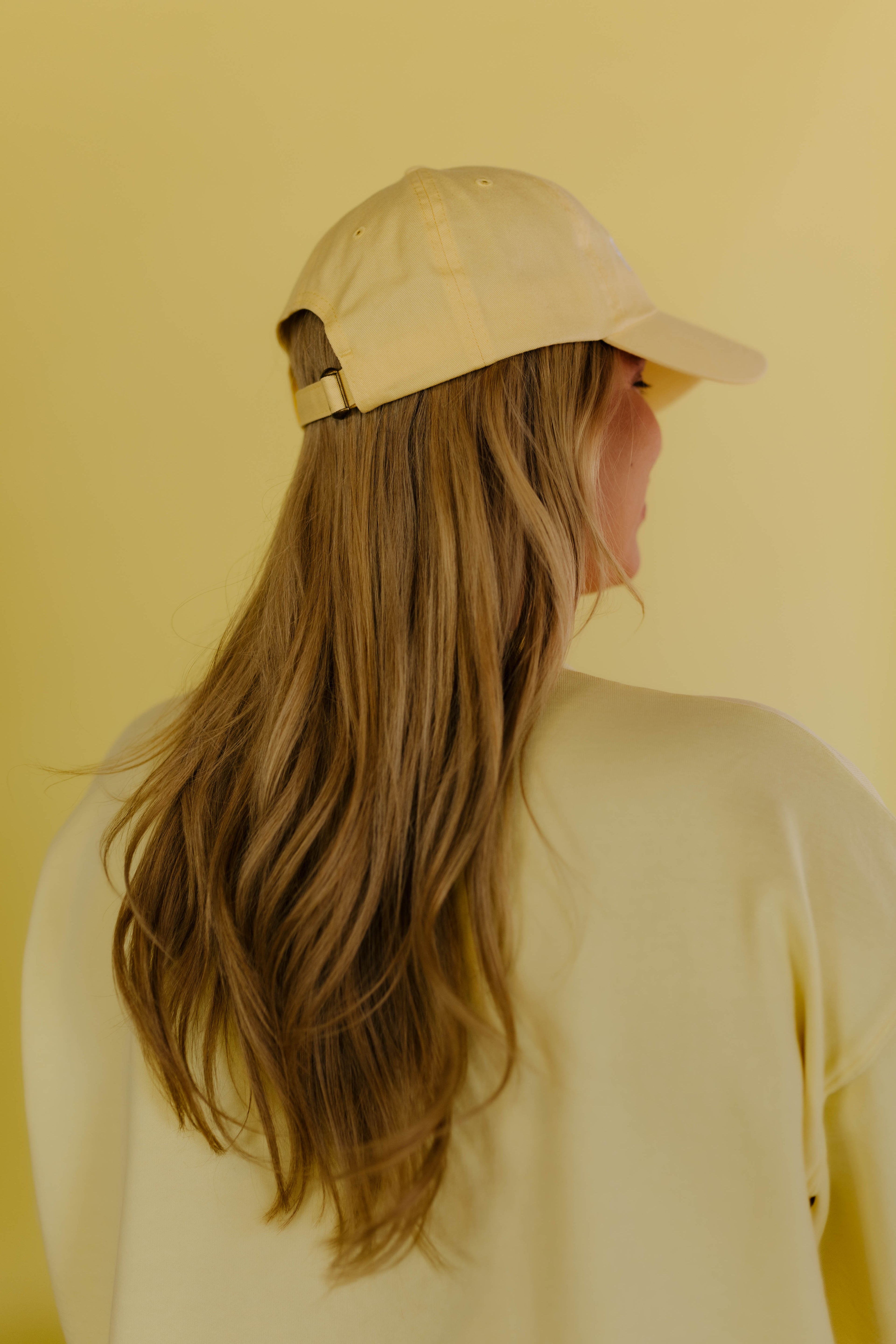 Person wearing a yellow hat against a yellow background