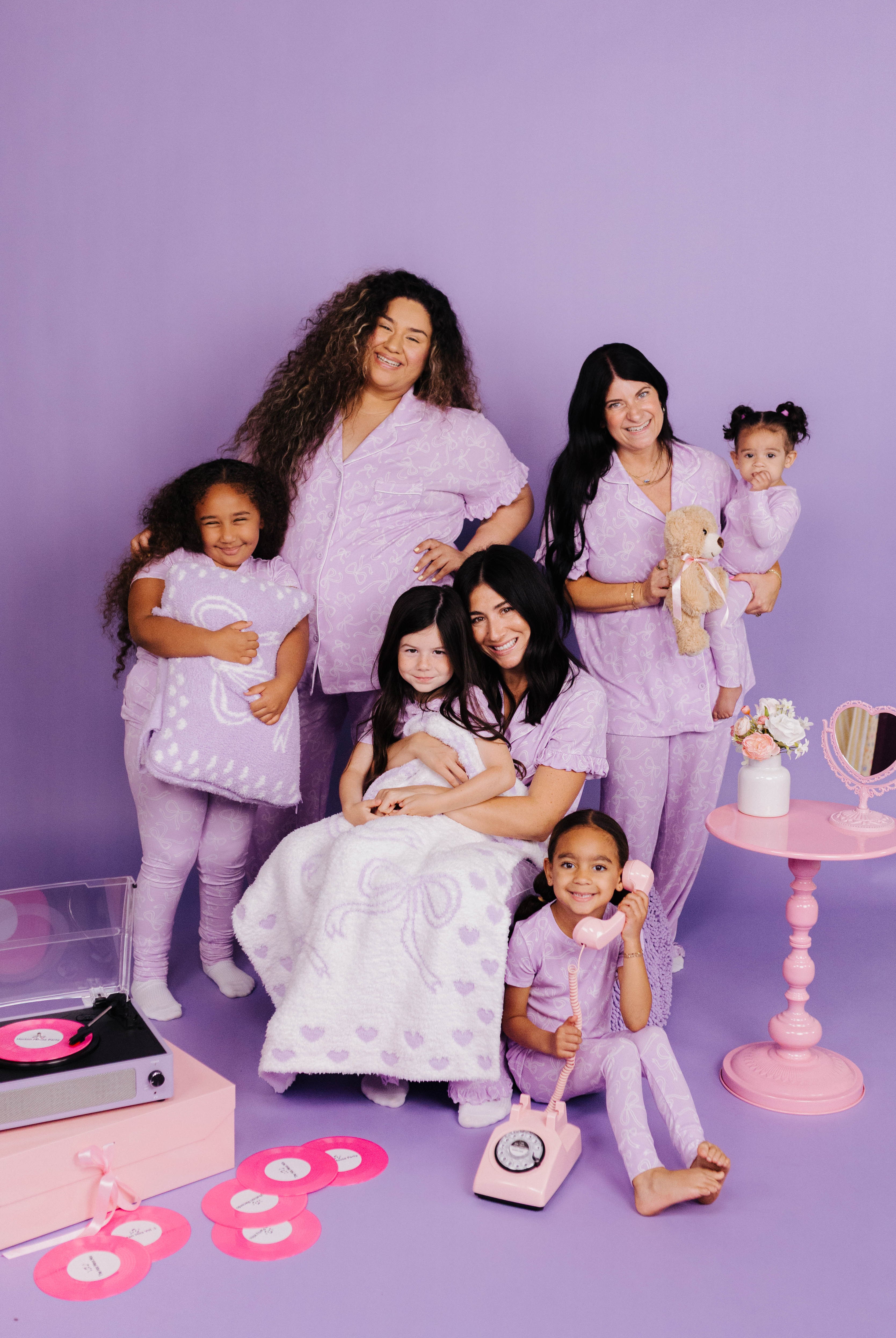 Models posing together in matching lavender outfits on a purple background