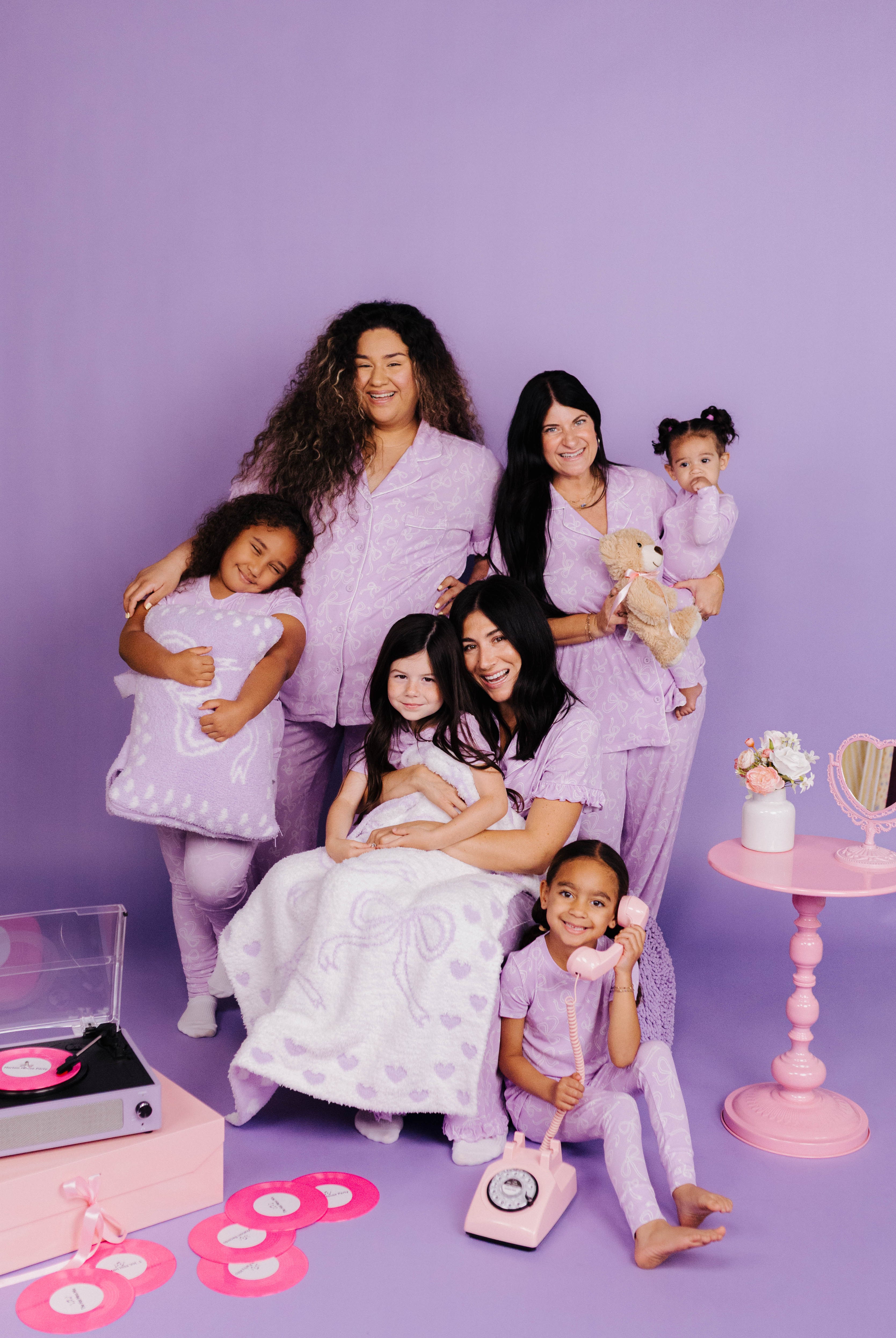 Friends in matching lavender outfits posing together on a purple background