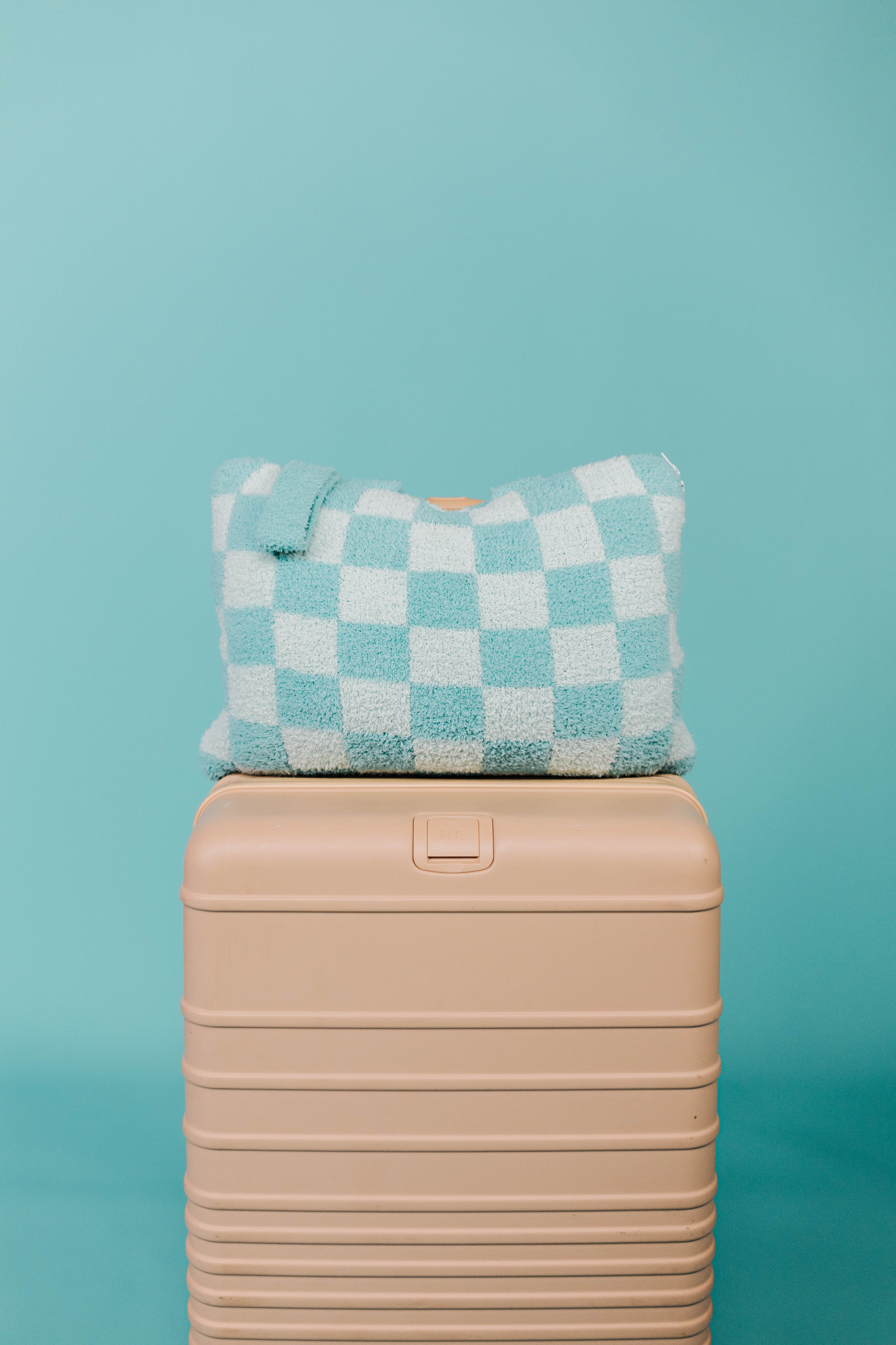 Checkered teal quillow on a beige suitcase