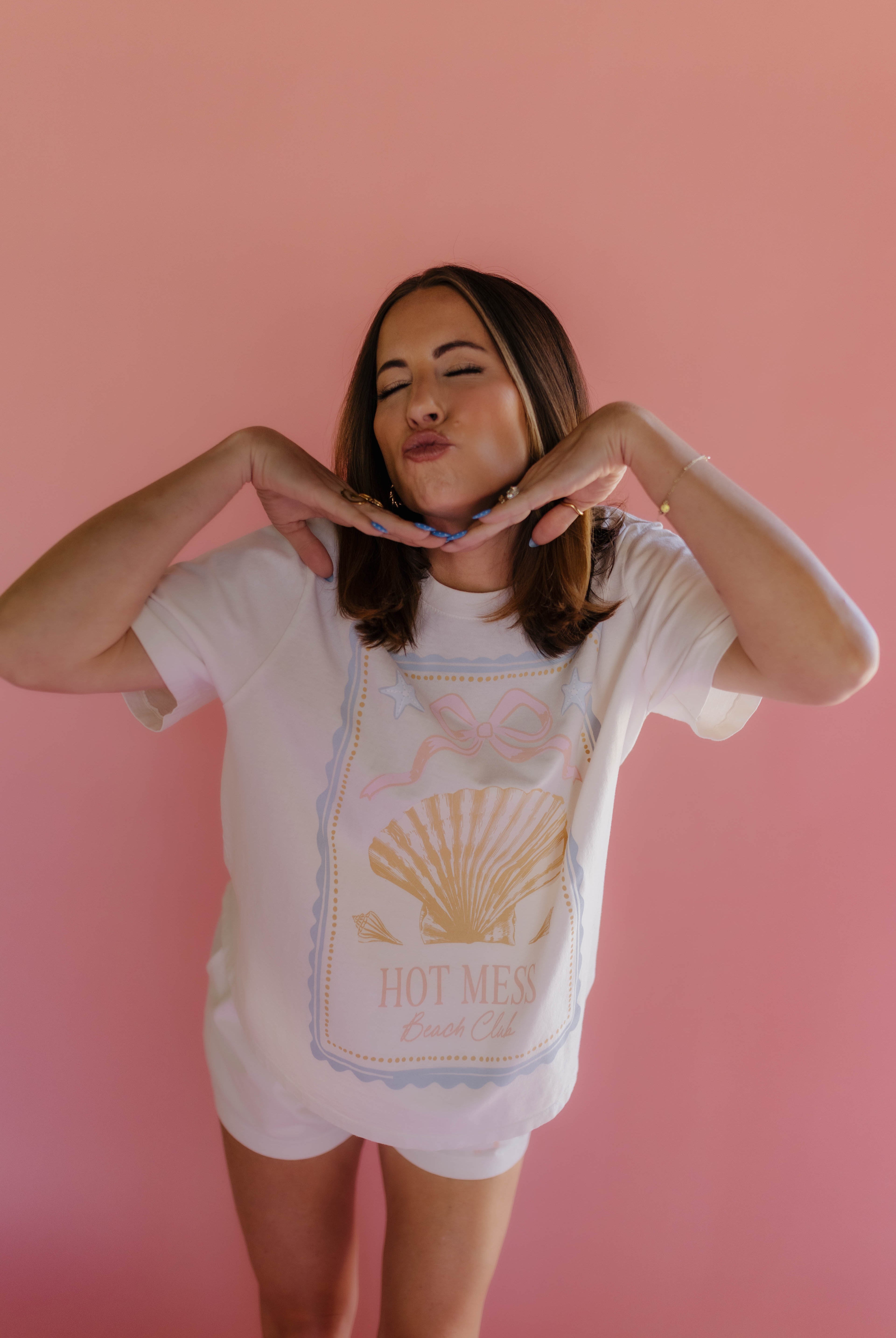 Woman wearing a white t-shirt with a graphic design on a pink background