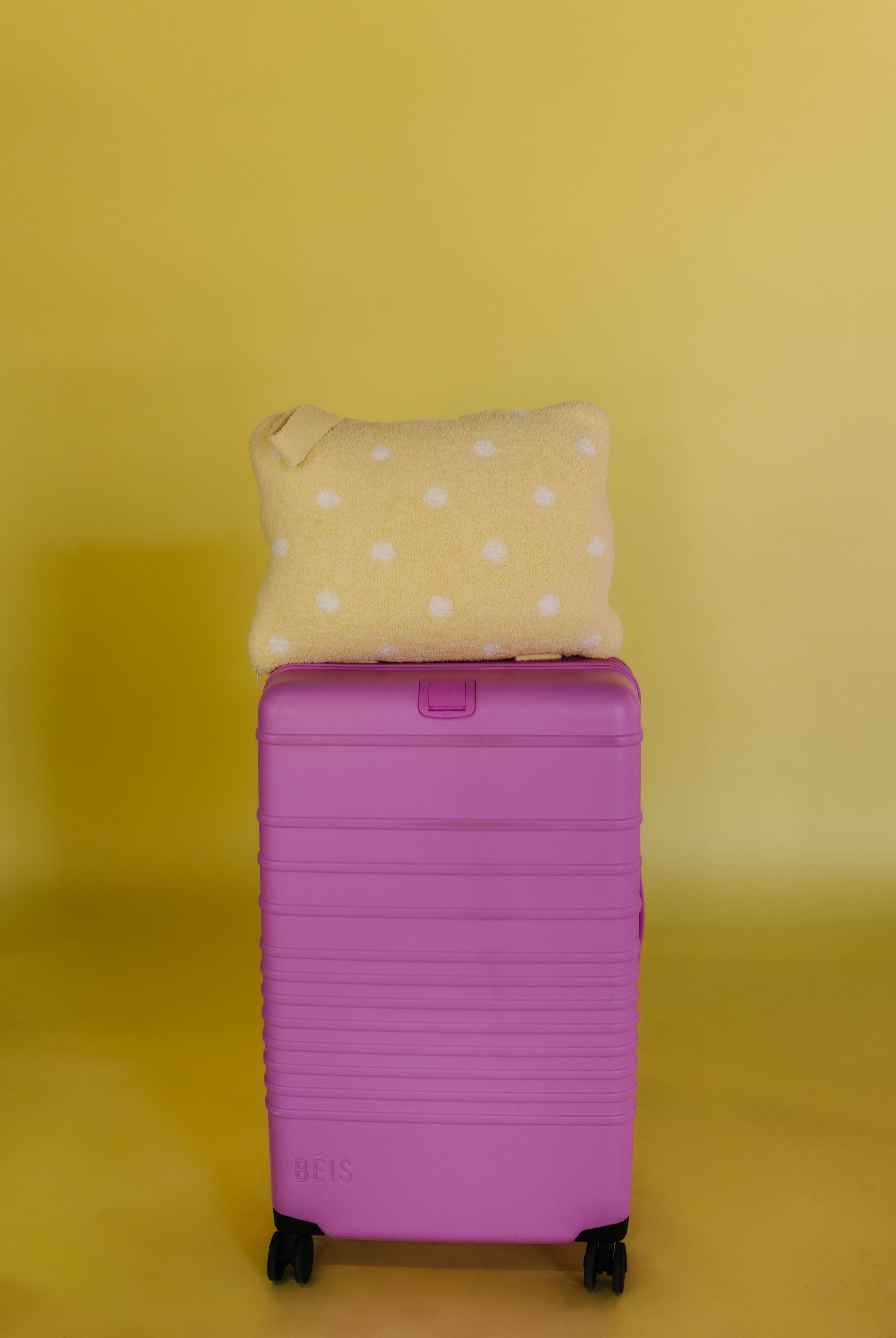 polka dot quillow on pink suitcase sitting on top of it