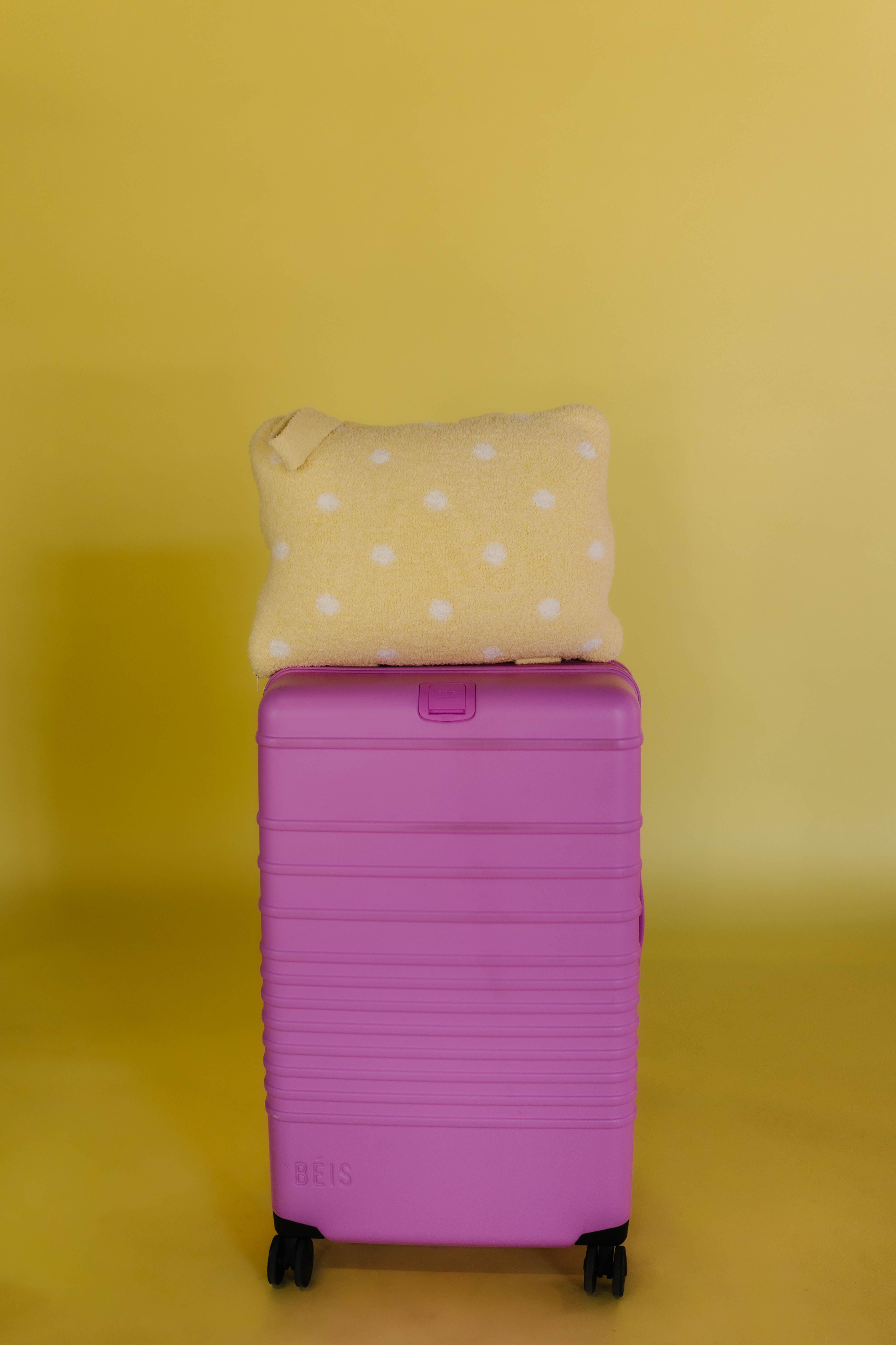 polka dot quillow on pink suitcase sitting on top of it