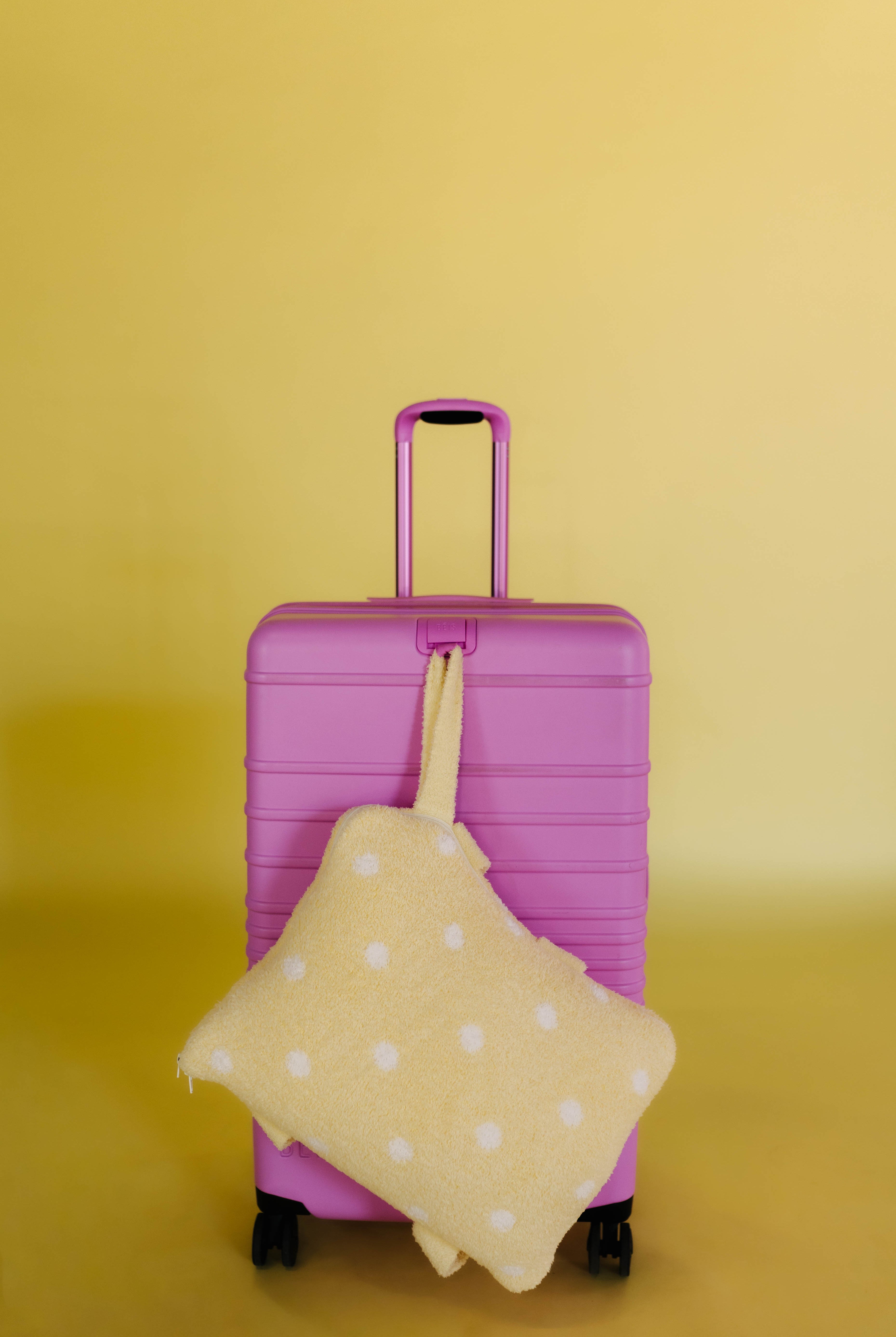 polka dot quillow hanging on the front of pink suitcase
