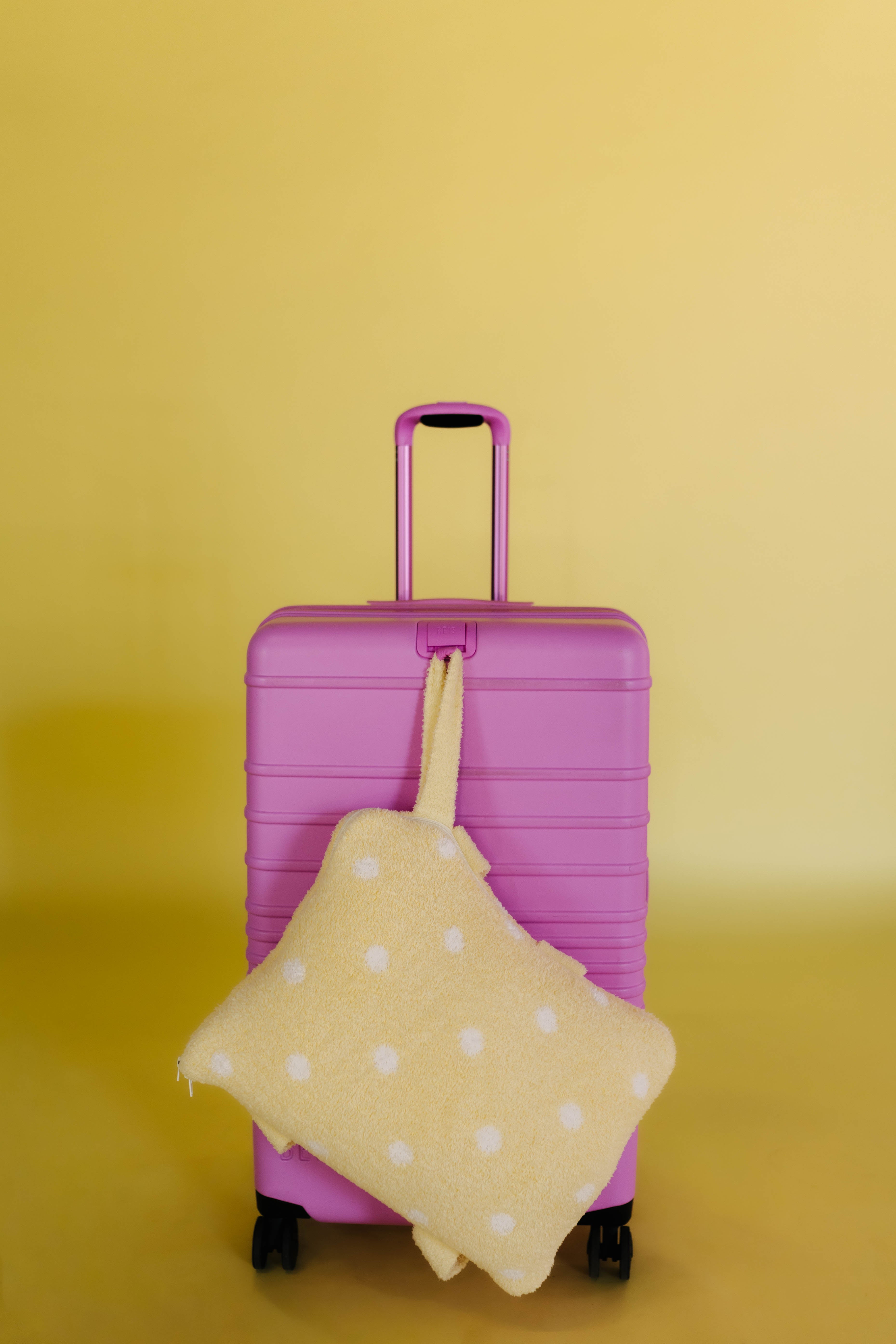 polka dot quillow hanging on the front of pink suitcase
