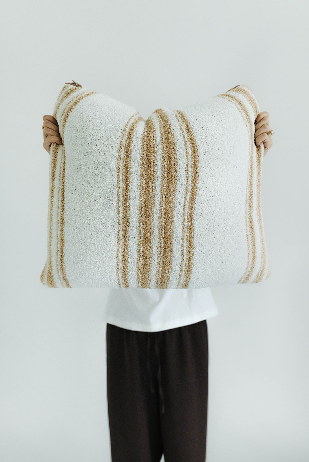 Person holding a striped quillow against a plain background