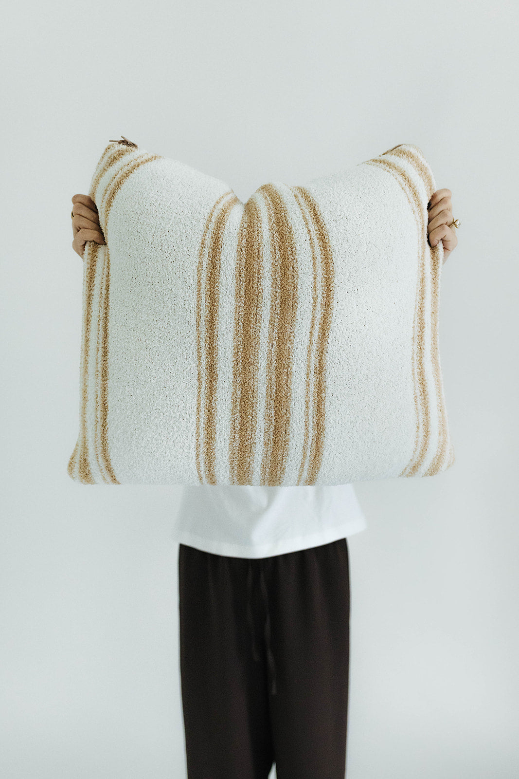 Person holding a striped quillow against a plain background