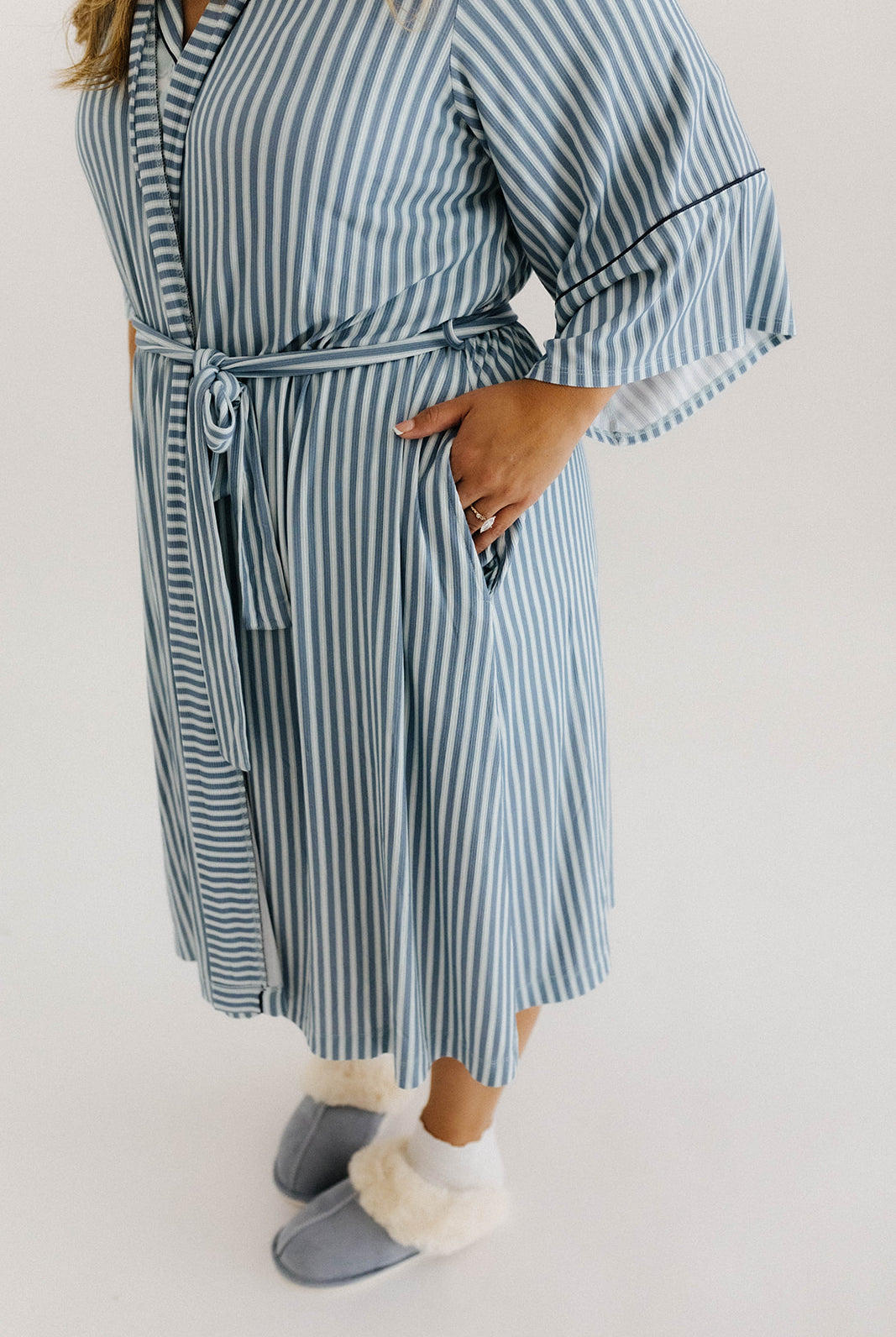 model with hands in pockets wearing blue striped robe