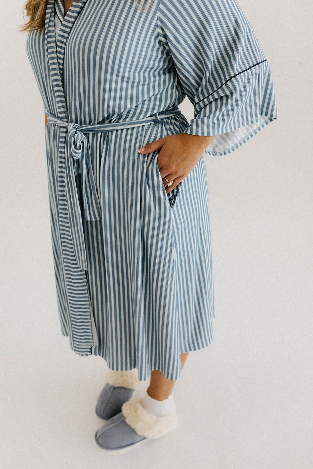 model with hands in pockets wearing blue striped robe