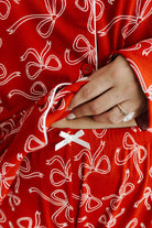 Red bow pajama set with white bow pattern and a hand holding a red fabric piece.