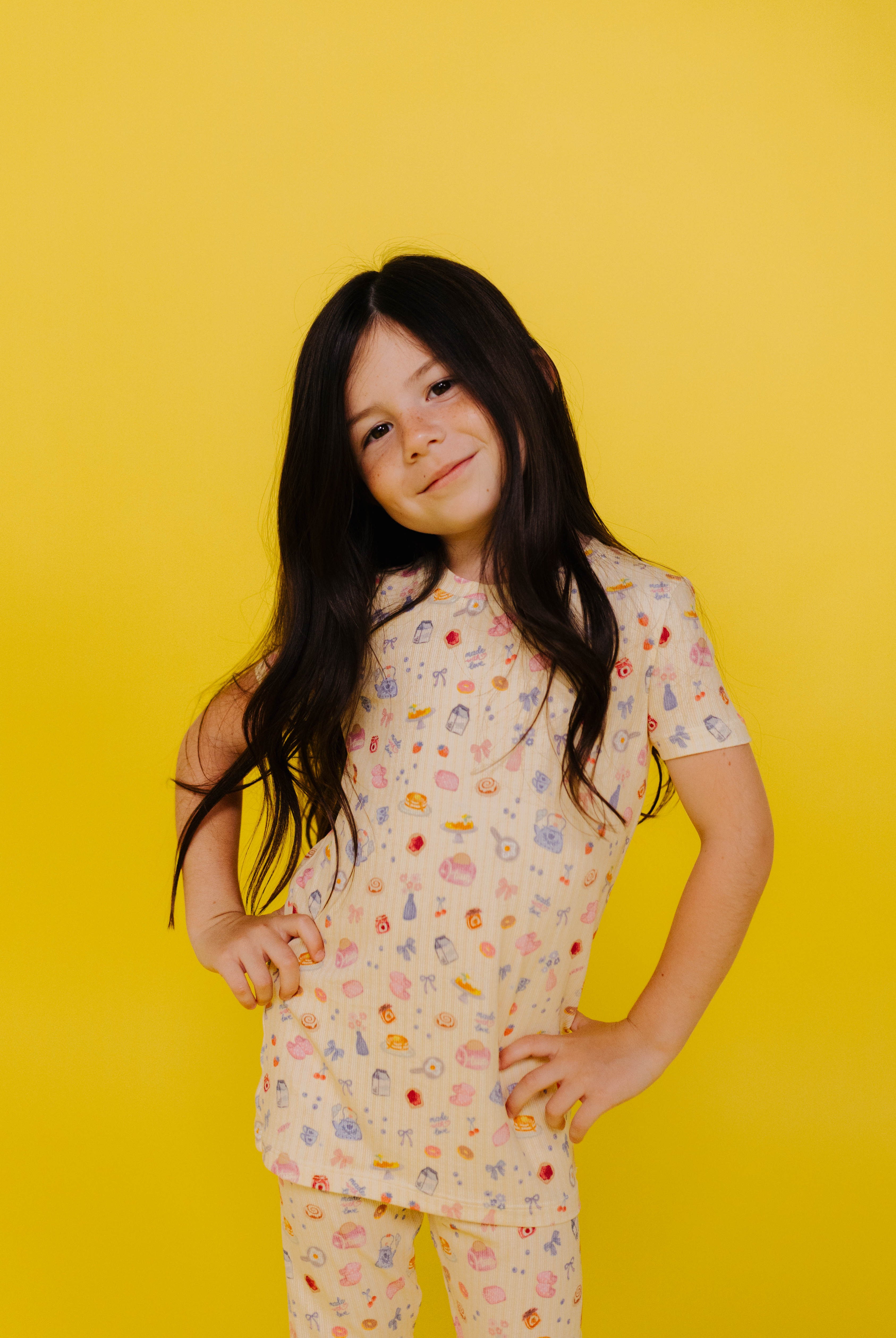 Young girl wearing a brunch pj set on a yellow background