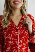 Person wearing a red pajama top with white bow pattern