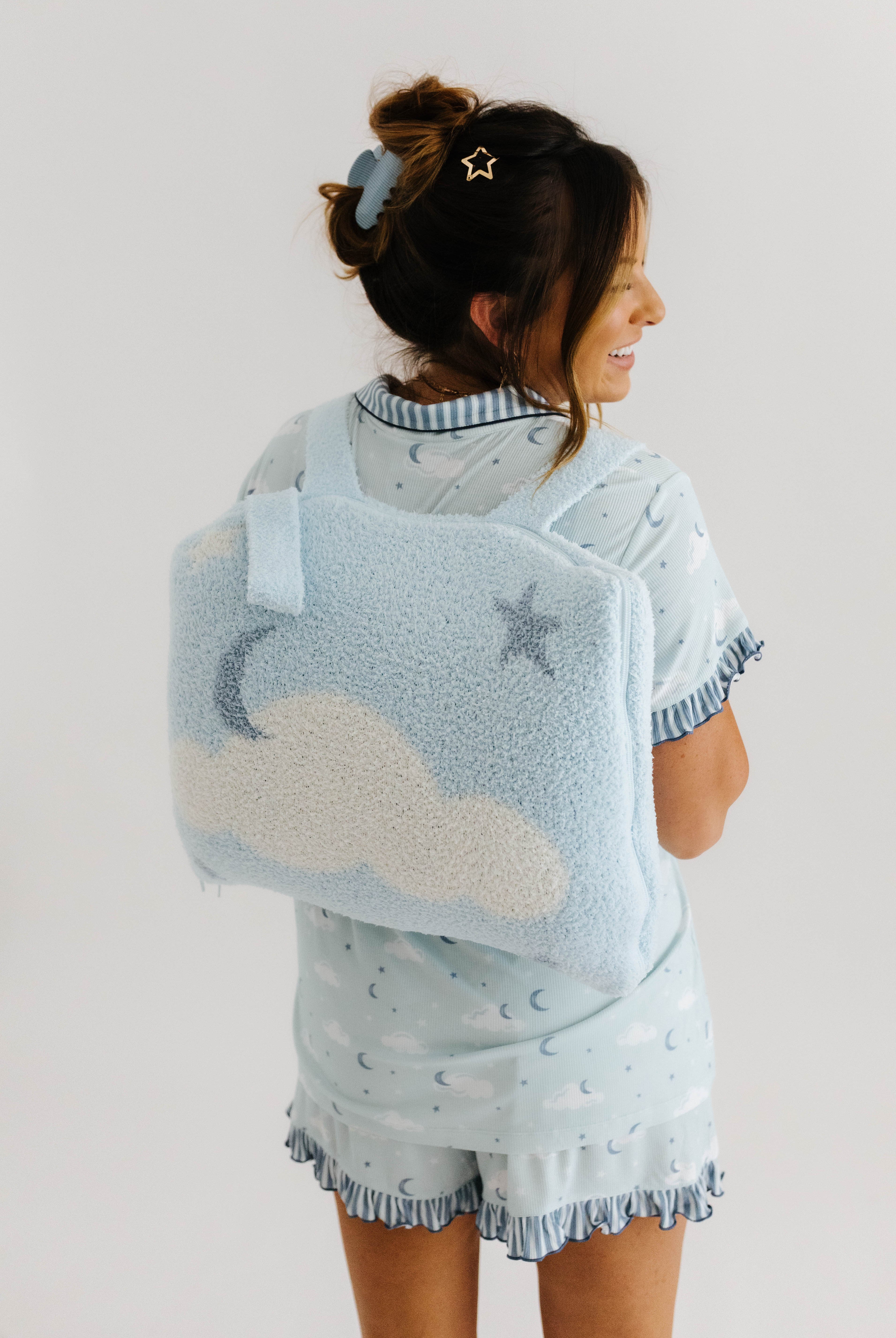 krista wearing cloud ruffle pajamas and cloud backpack/wristlet quillow on back