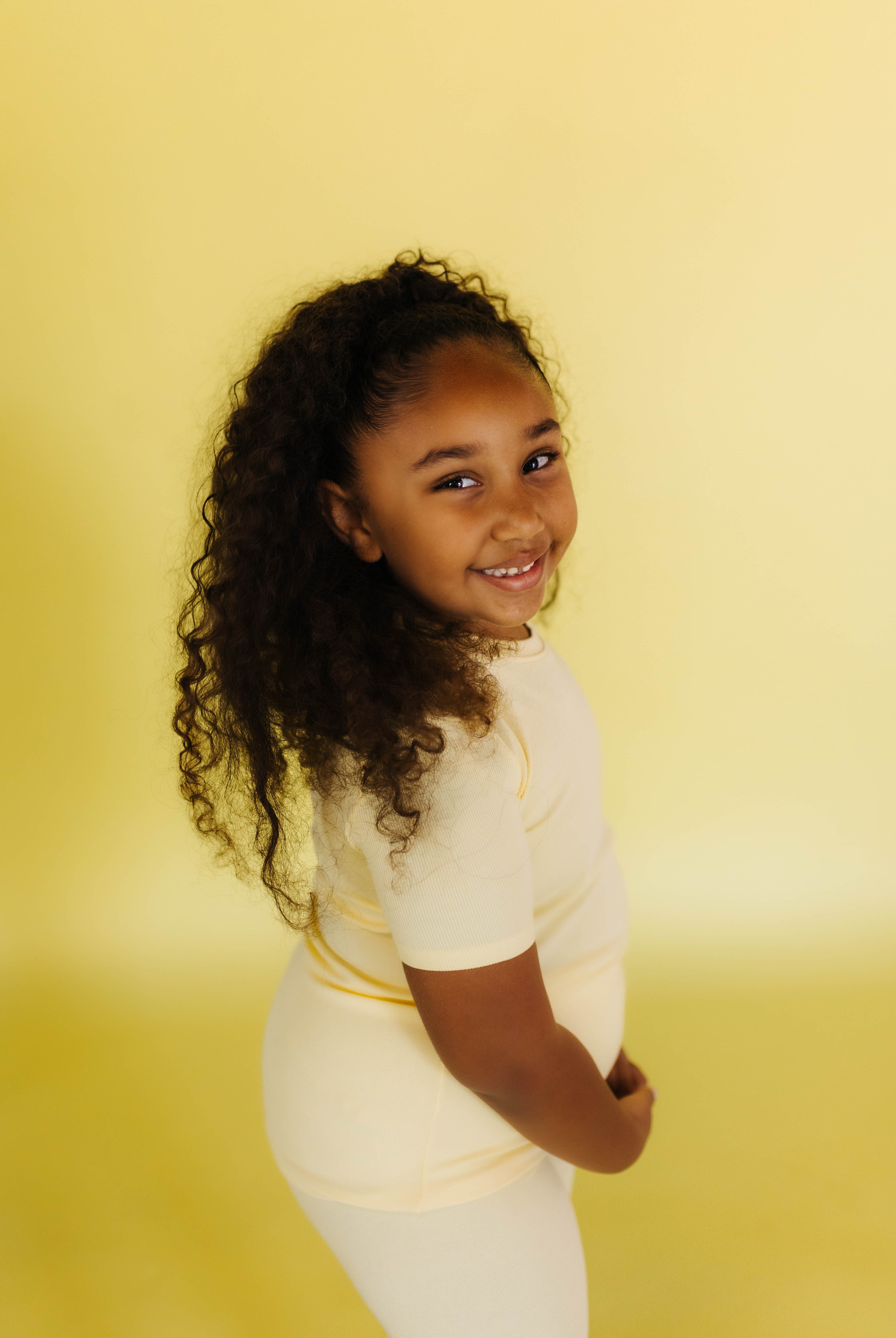 Isla smiling in the yellow pjs against a yellow backdrop