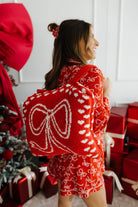 Woman wearing a red bow pajama set in a festive setting with Christmas decorations.