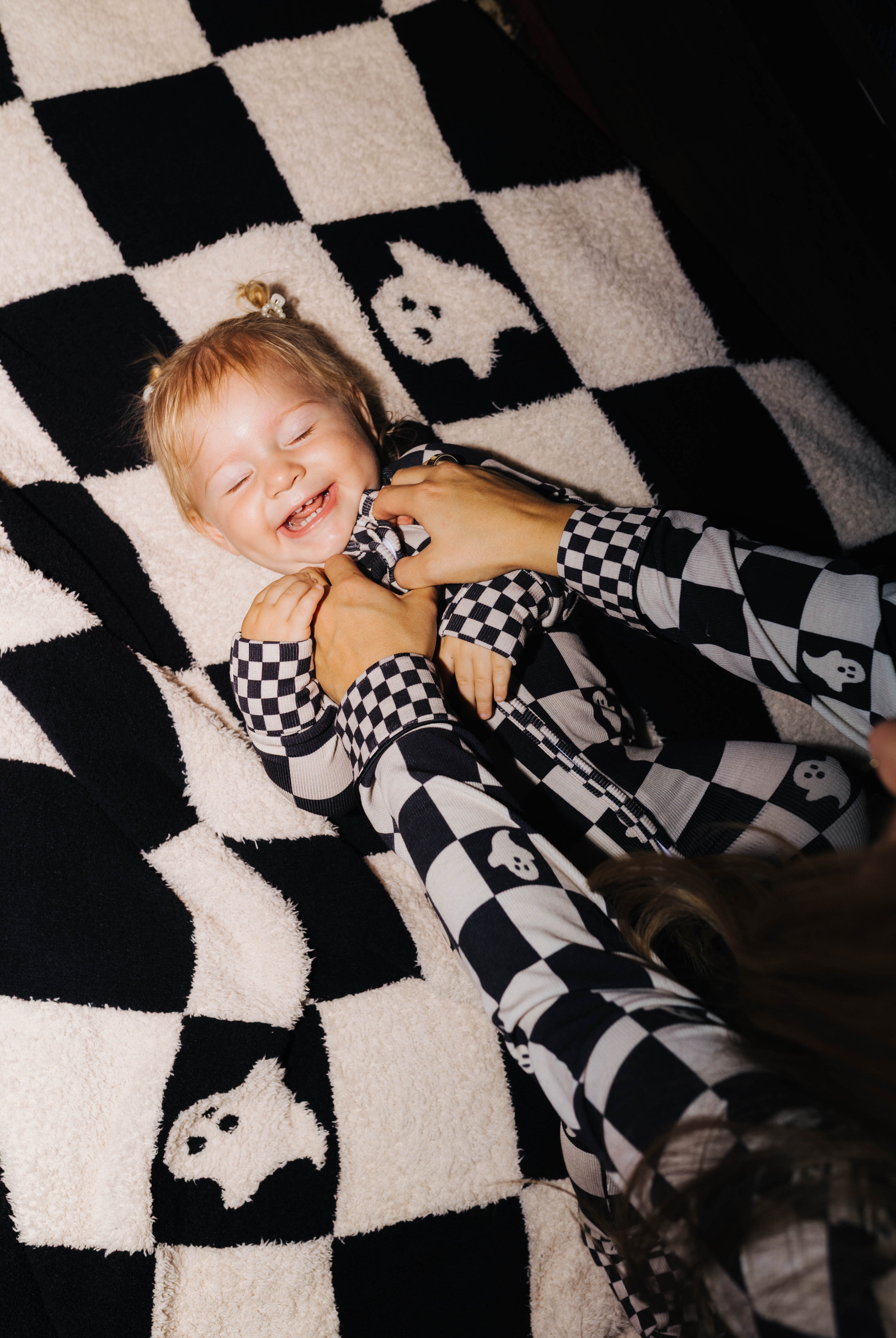 Baby wearing Ghost Check zip pajamas on the matching blanket
