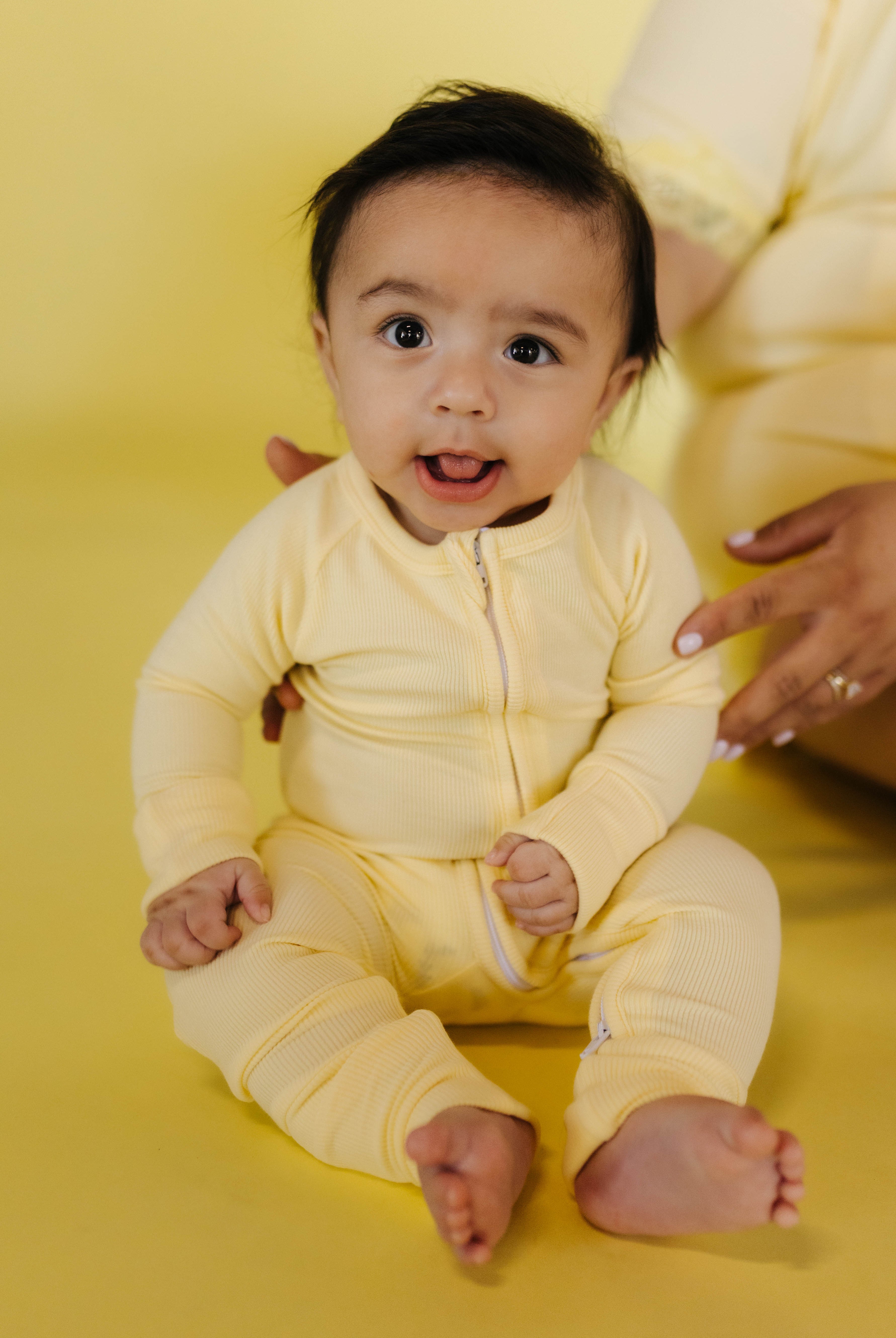 baby sitting in the butter yellow pjs on a butter yellow background