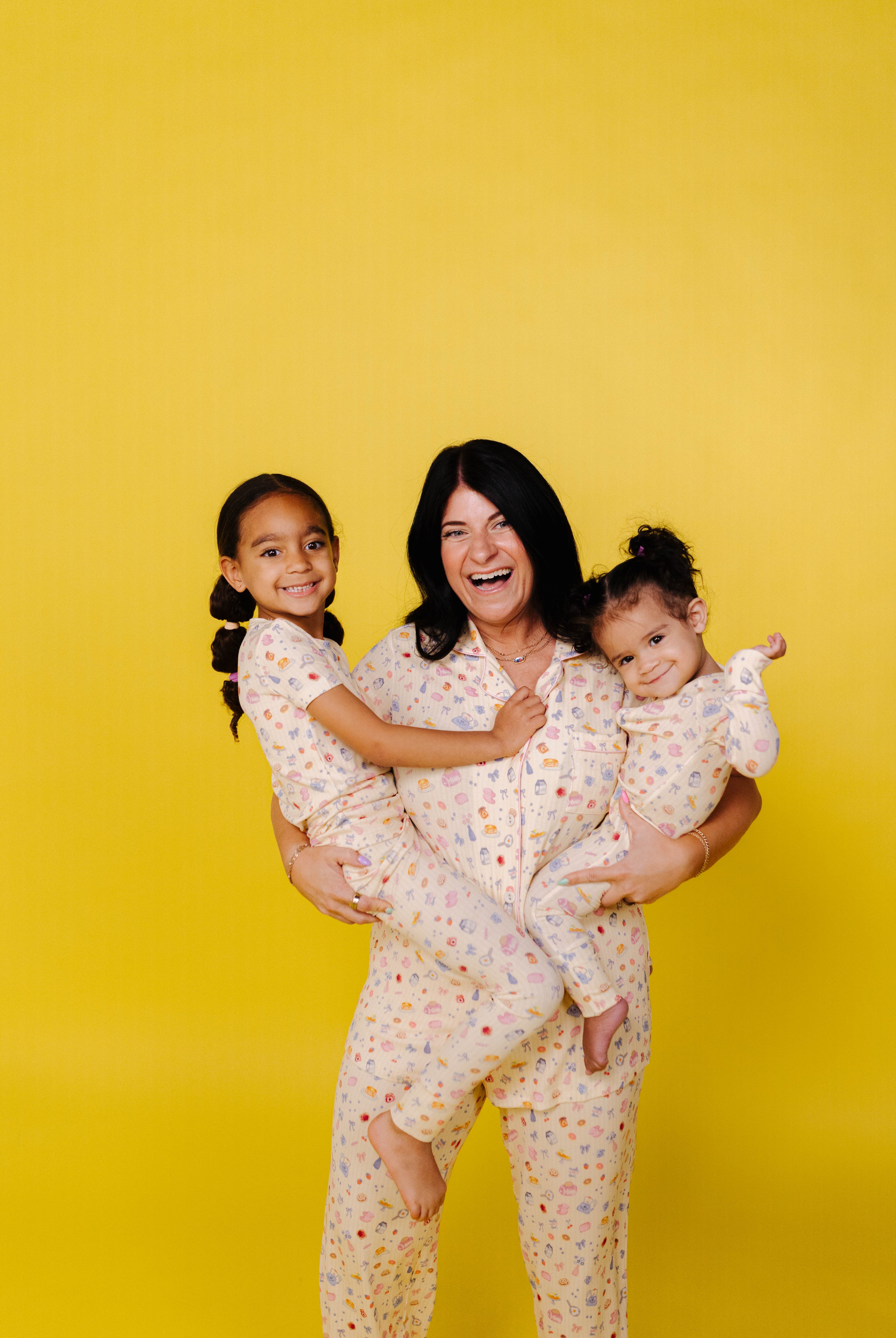 Woman and two children in matching pajamas against a yellow background