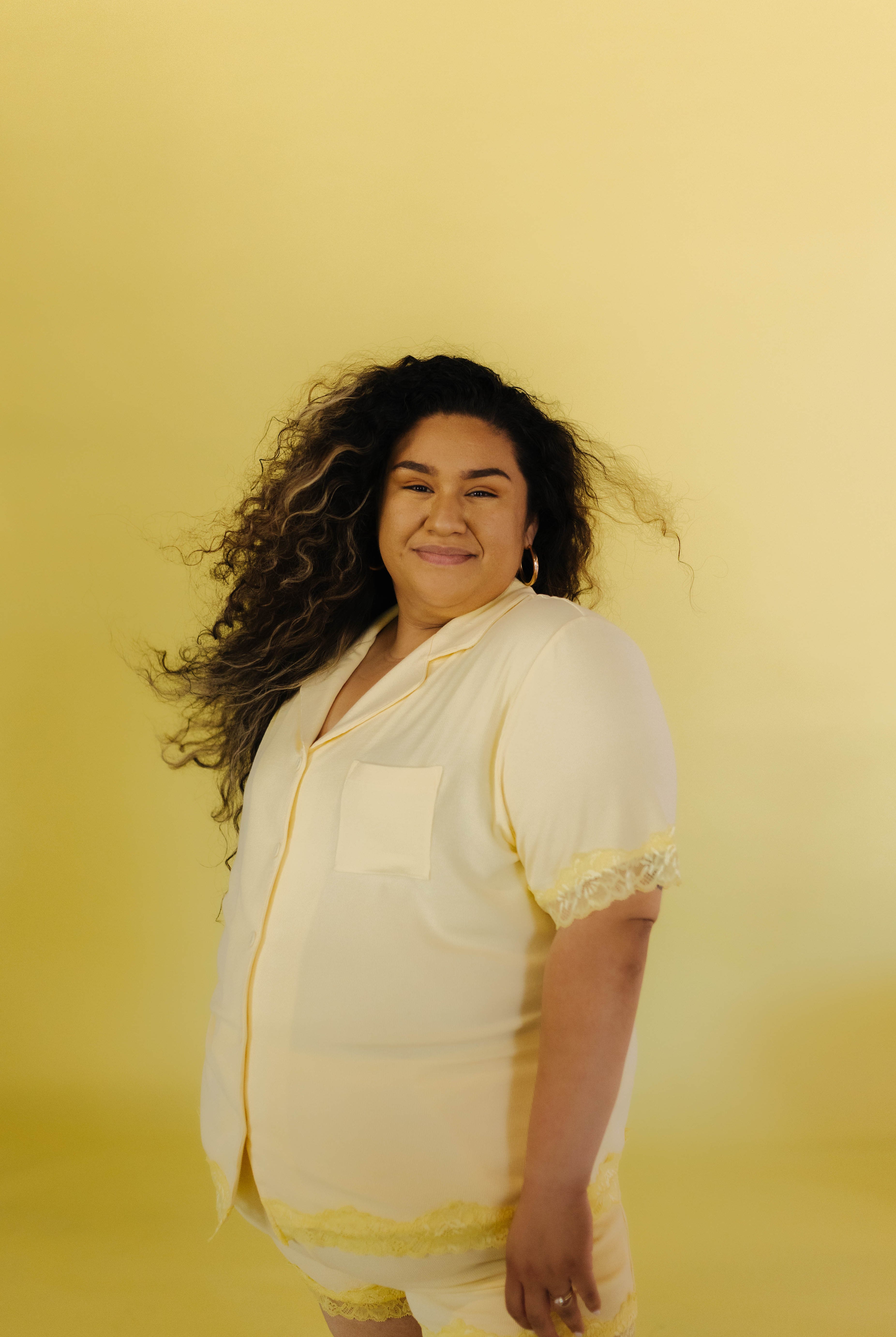 Perla modeling the 3xl in front of a yellow backdrops