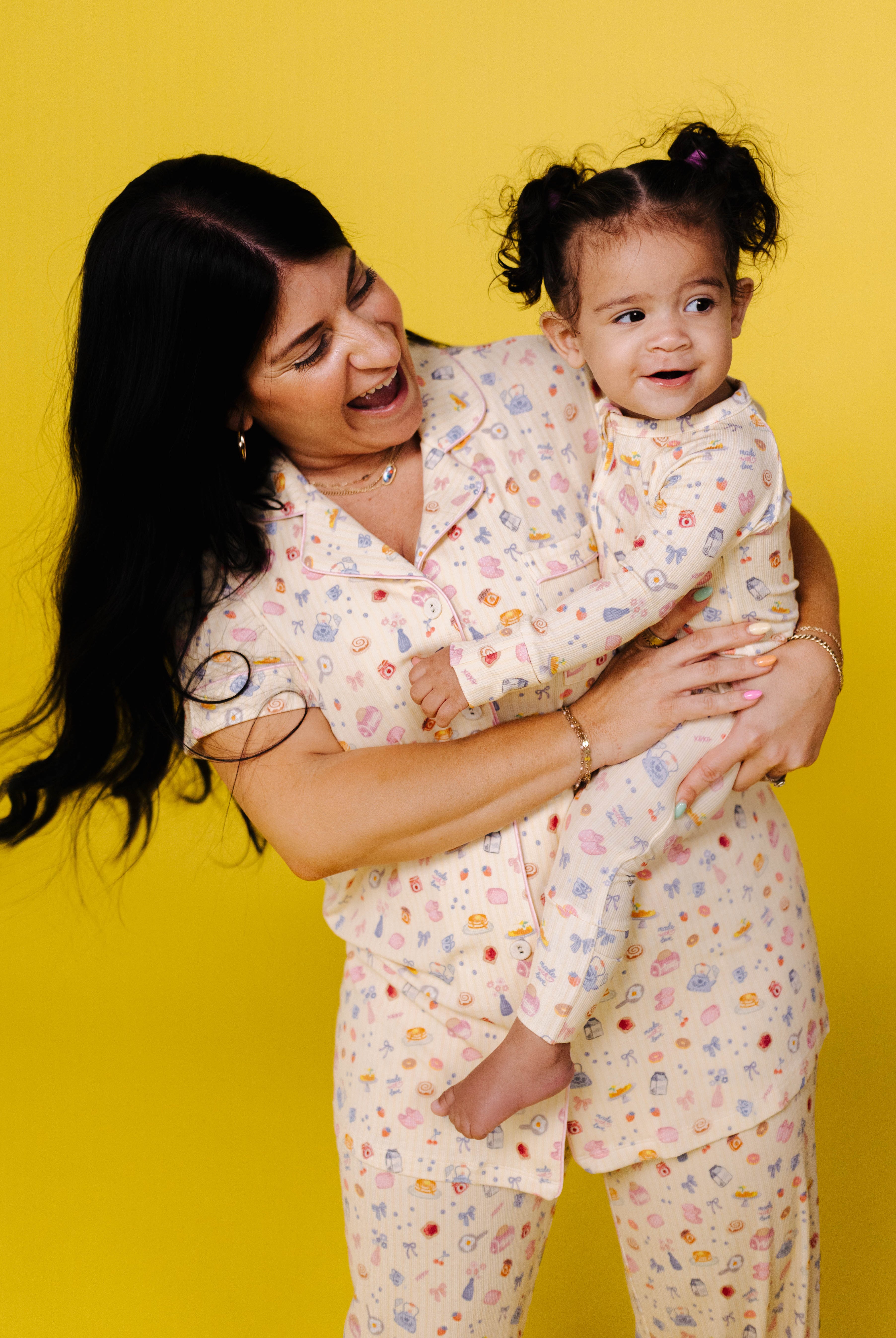 Woman and child in matching pajamas against a yellow background