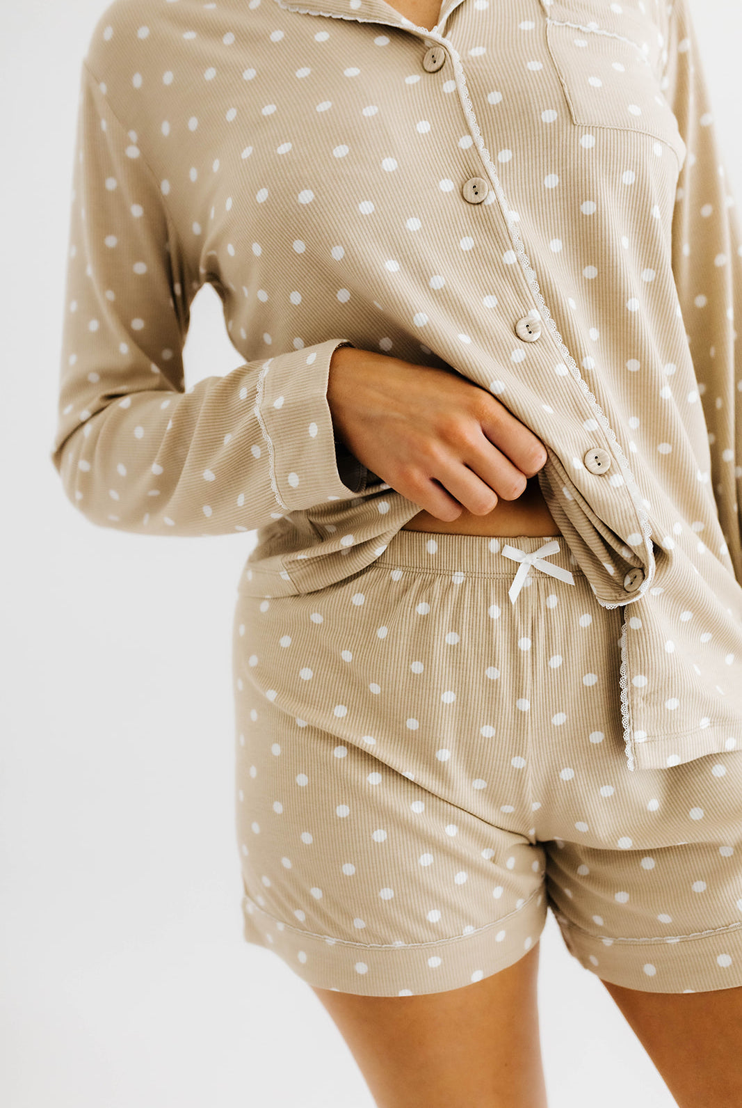 model lifting top of polka dot pajamas to show bottoms of the polka dot pajama shorts