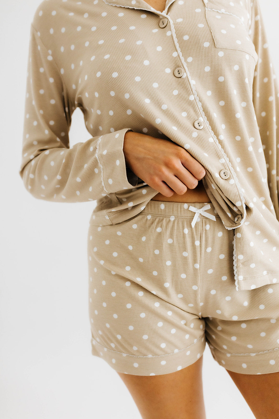 model lifting top of polka dot pajamas to show bottoms of the polka dot pajama shorts