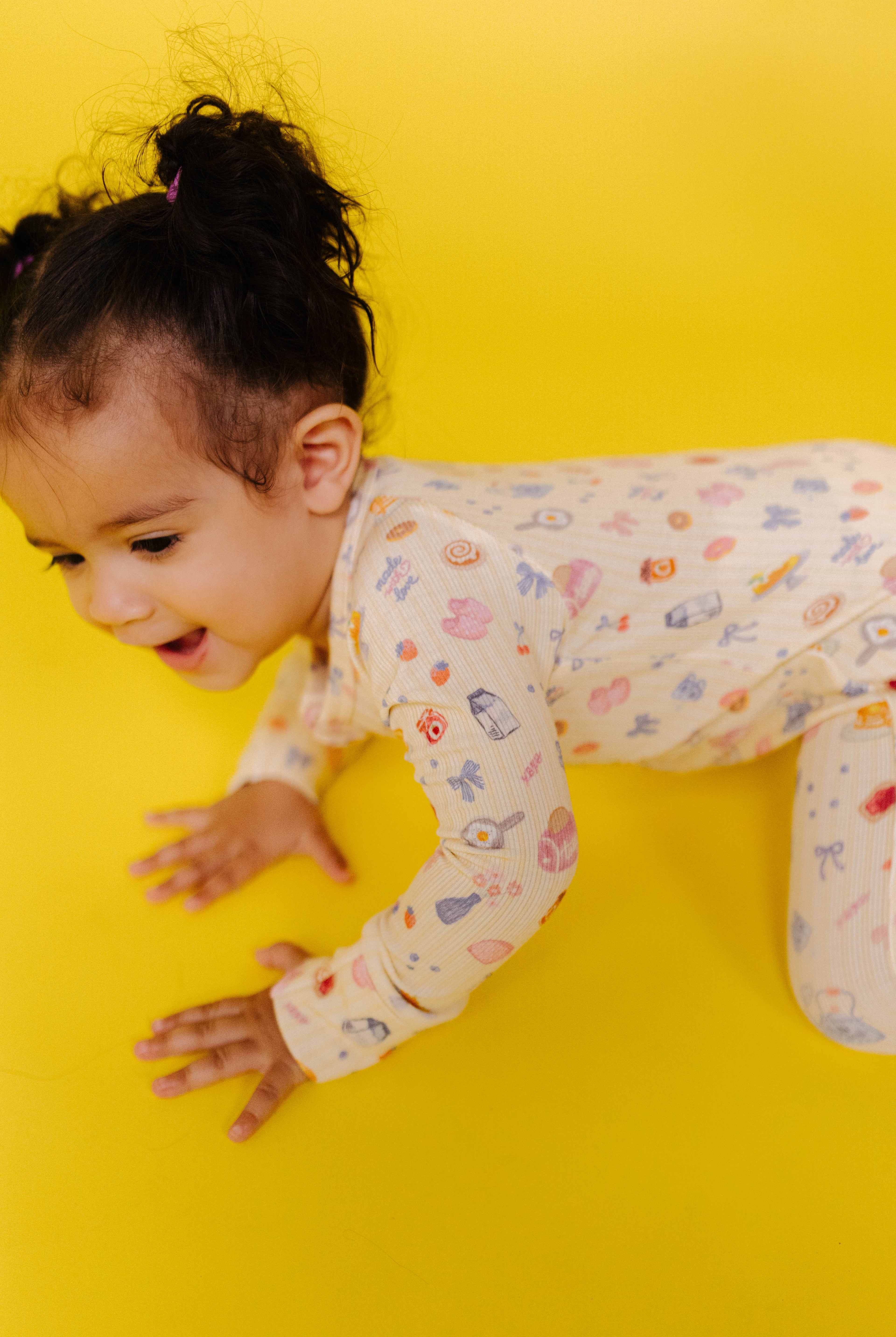 Child in pajamas crawling on a yellow background