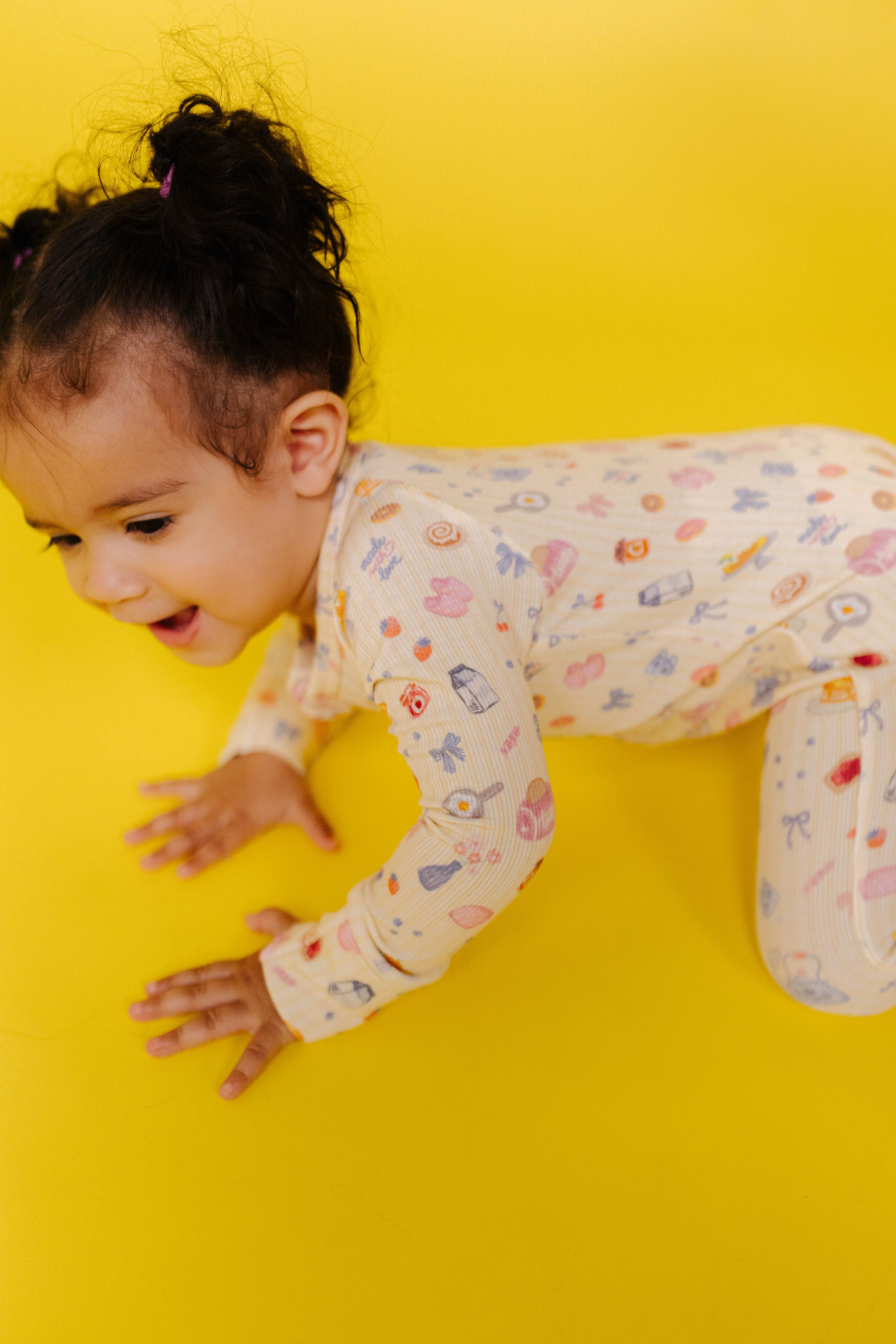 Child in pajamas crawling on a yellow background