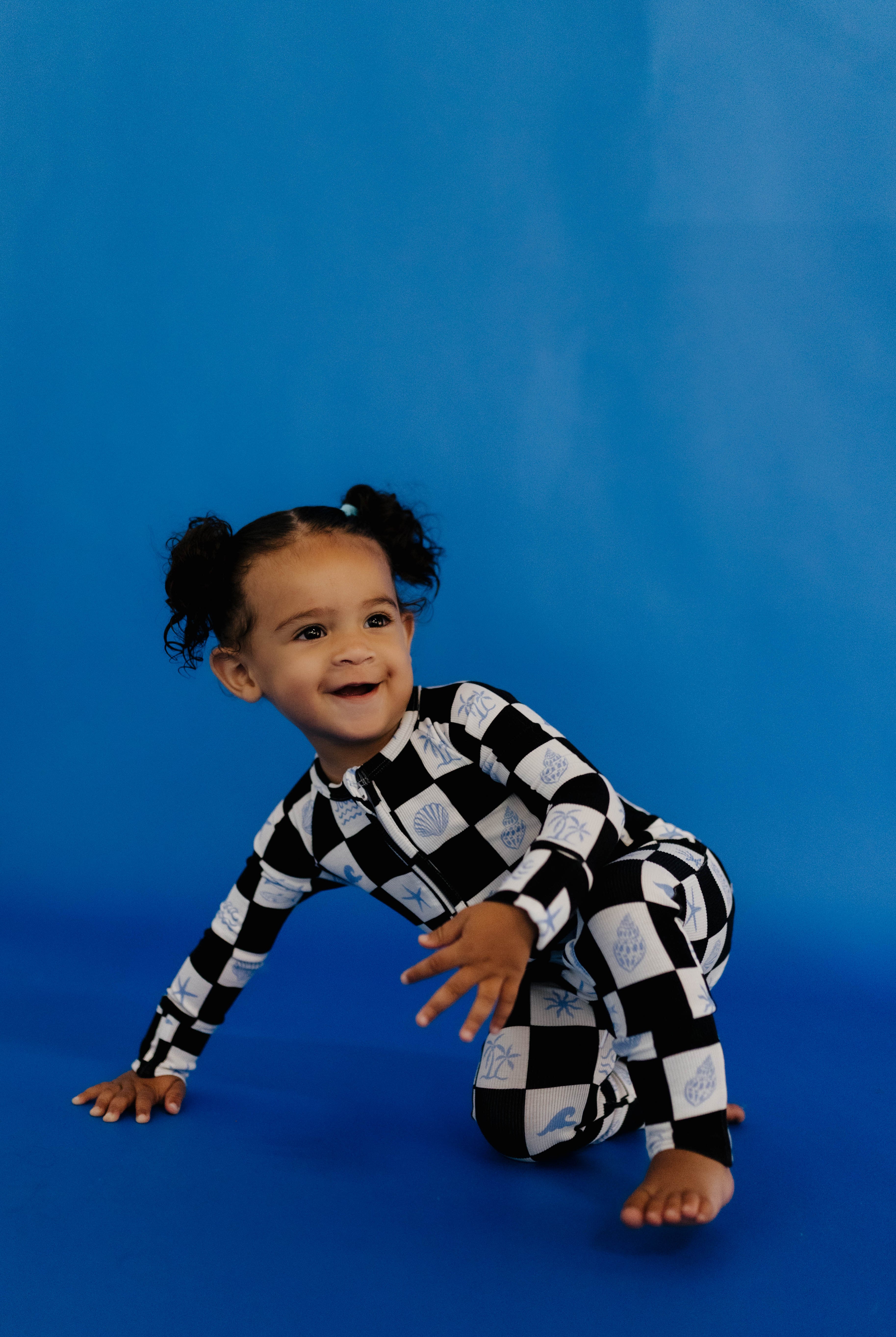 Child wearing a black and white checkered outfit on a blue background size 3-6 months