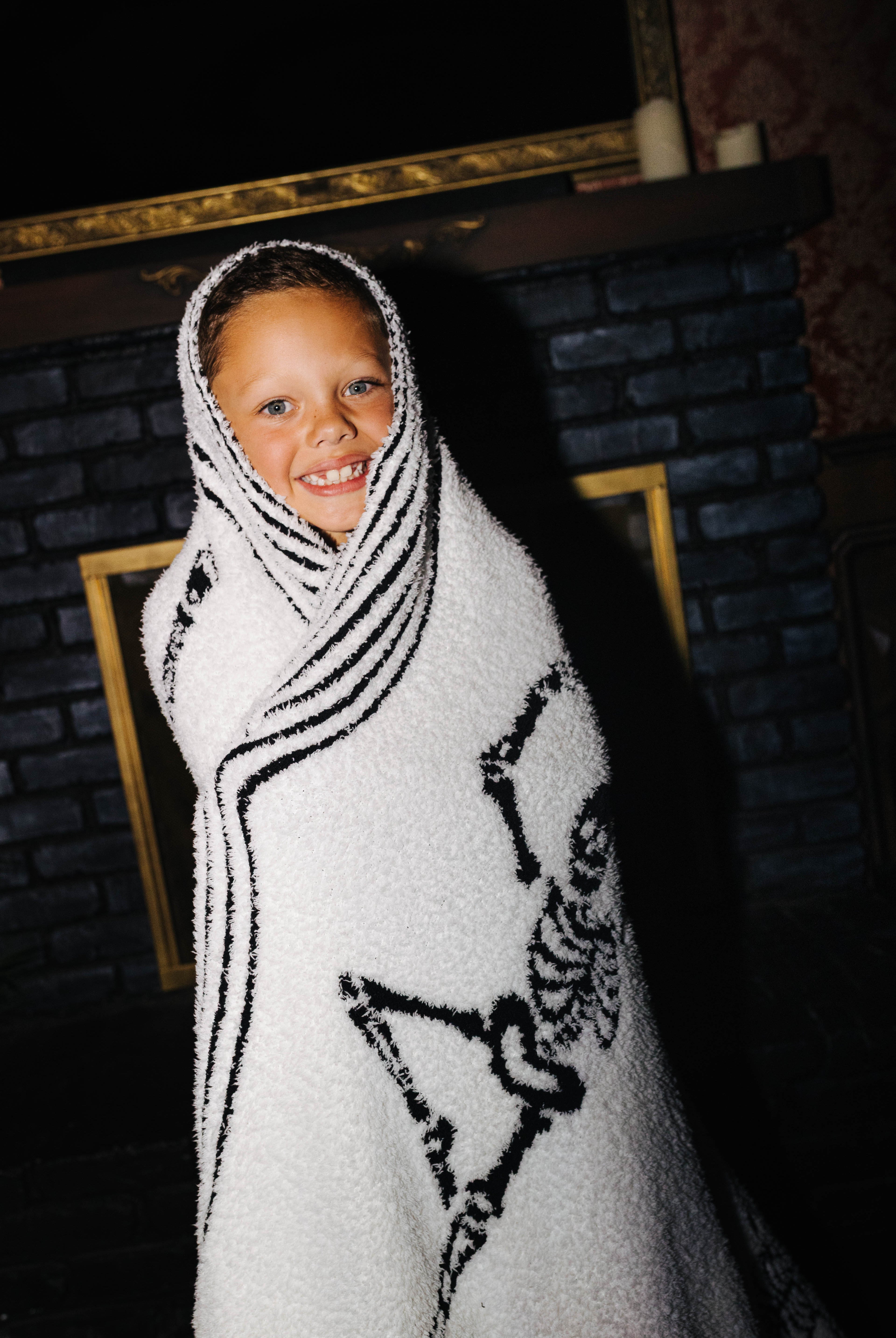Child wrapped in the reverse side of the Skelly blanket