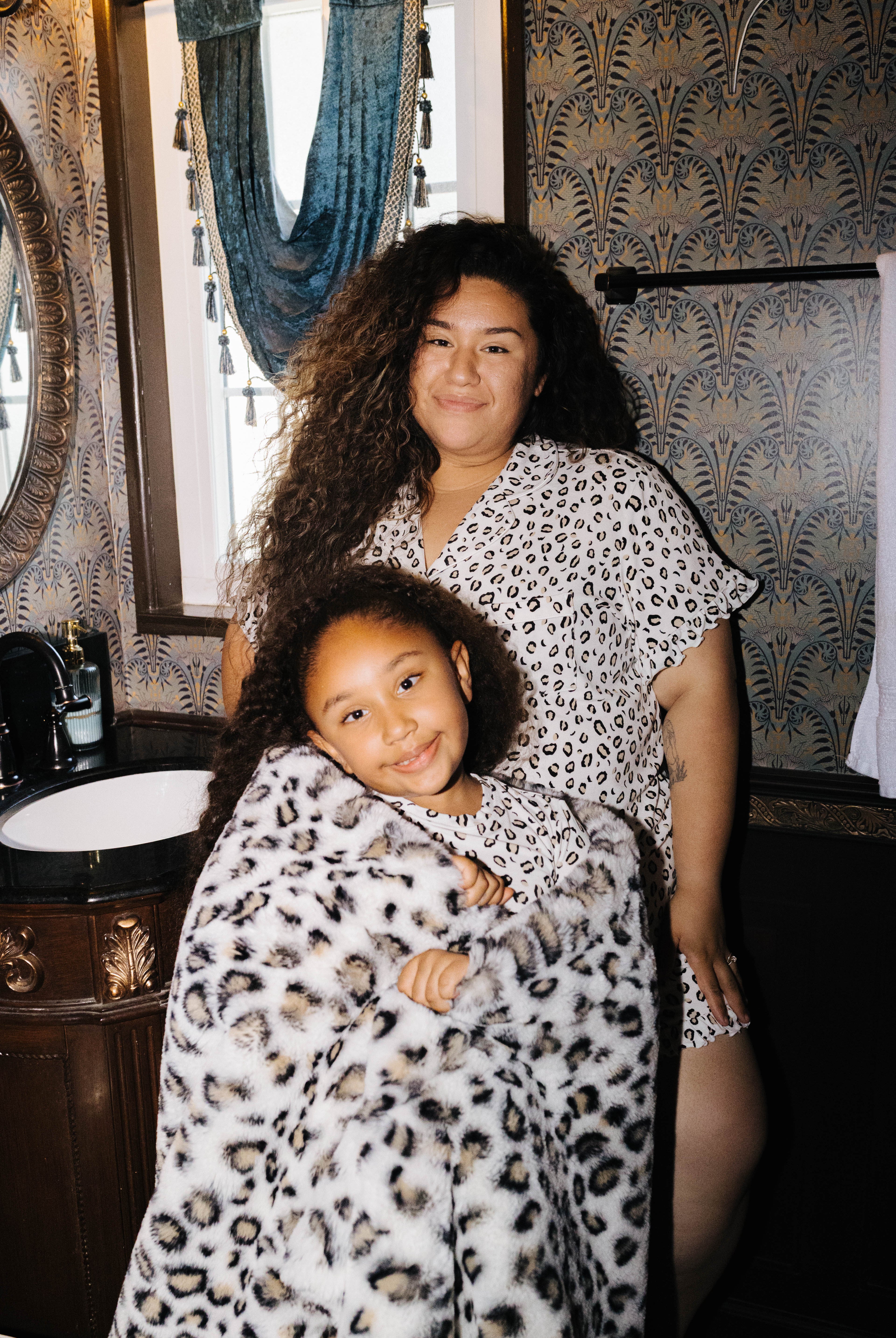 Adult and child wearing matching leopard pajamas with a leopard blanket