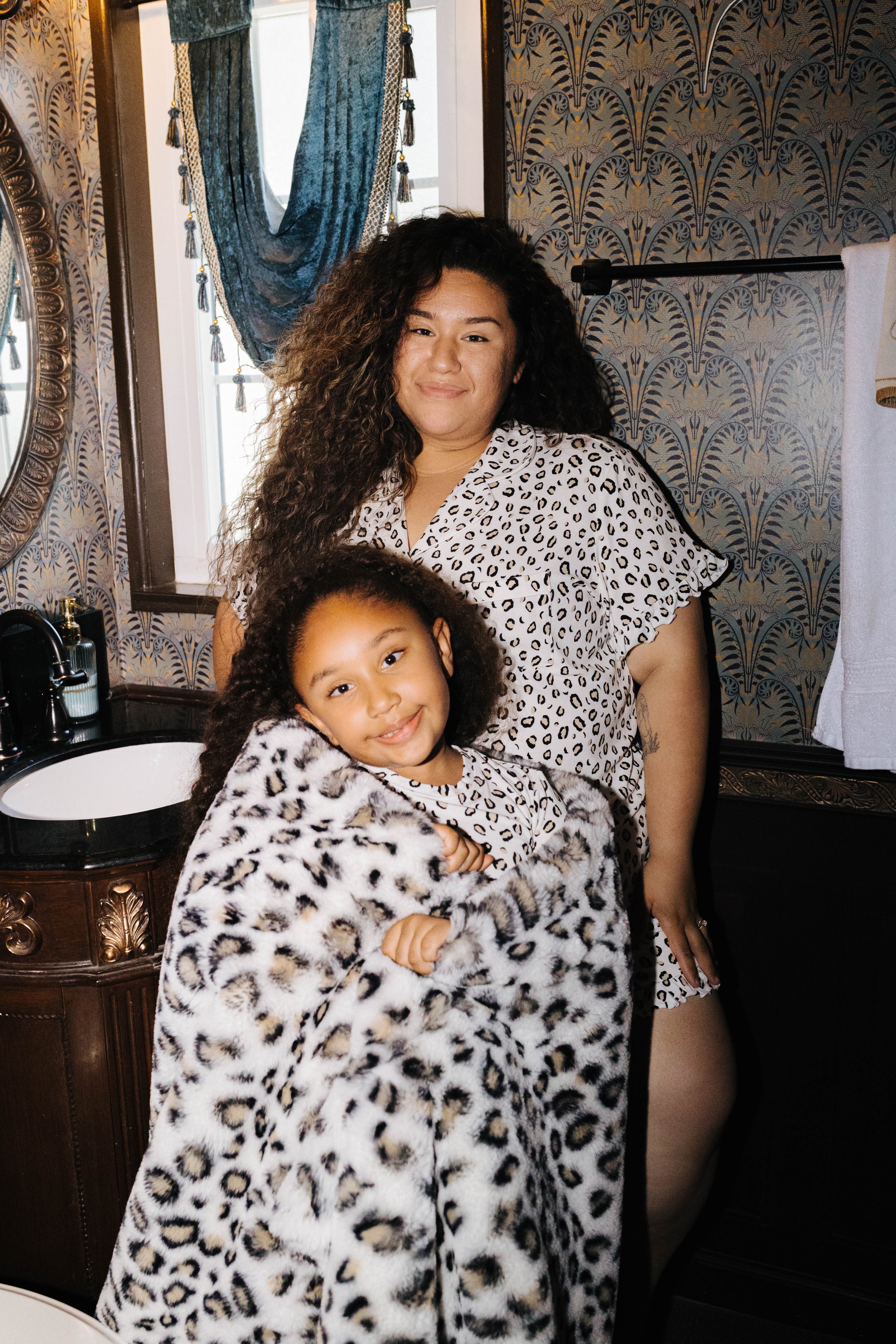 Adult and child wearing matching leopard pajamas with a leopard blanket