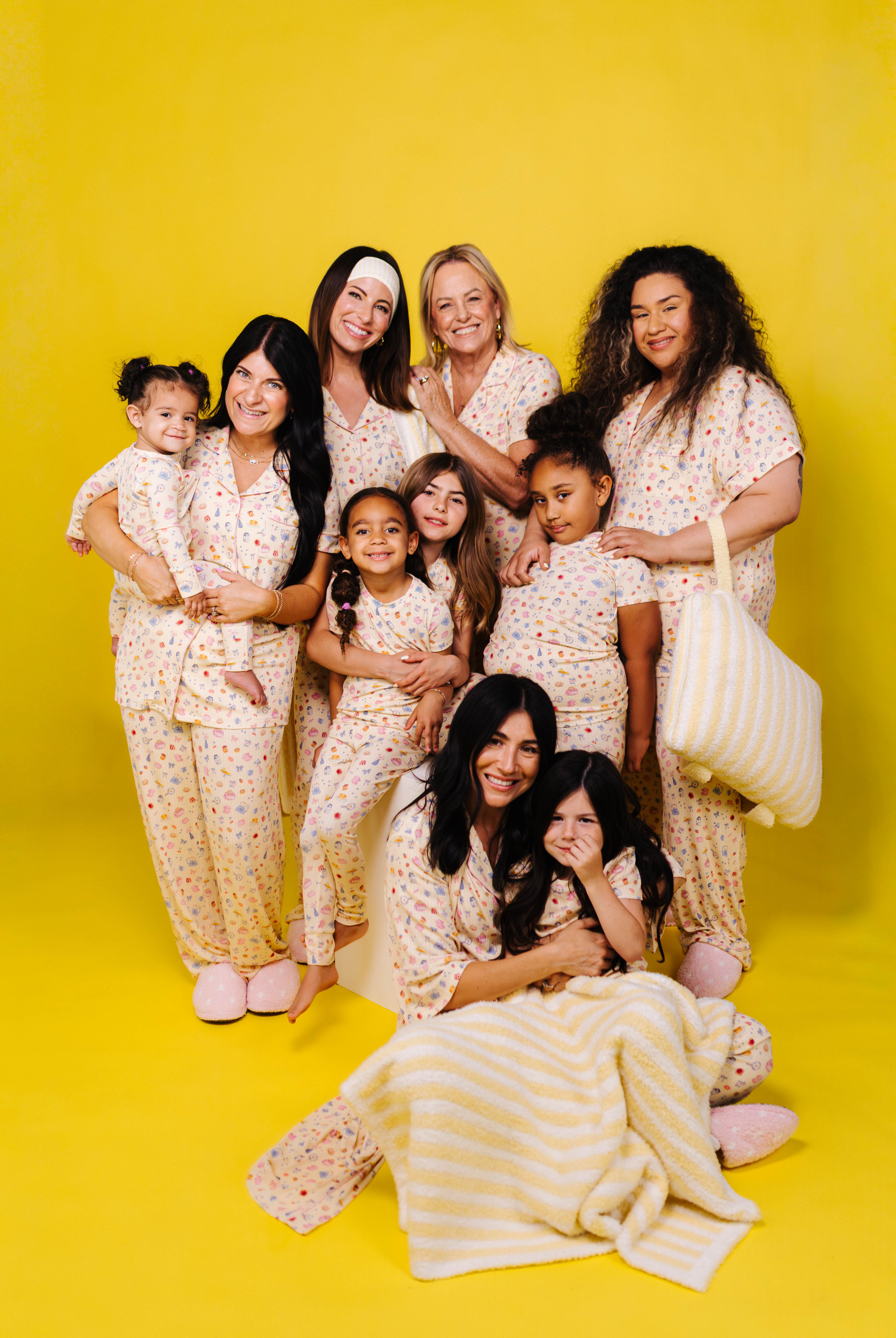 Group of women and children in matching outfits against a yellow background