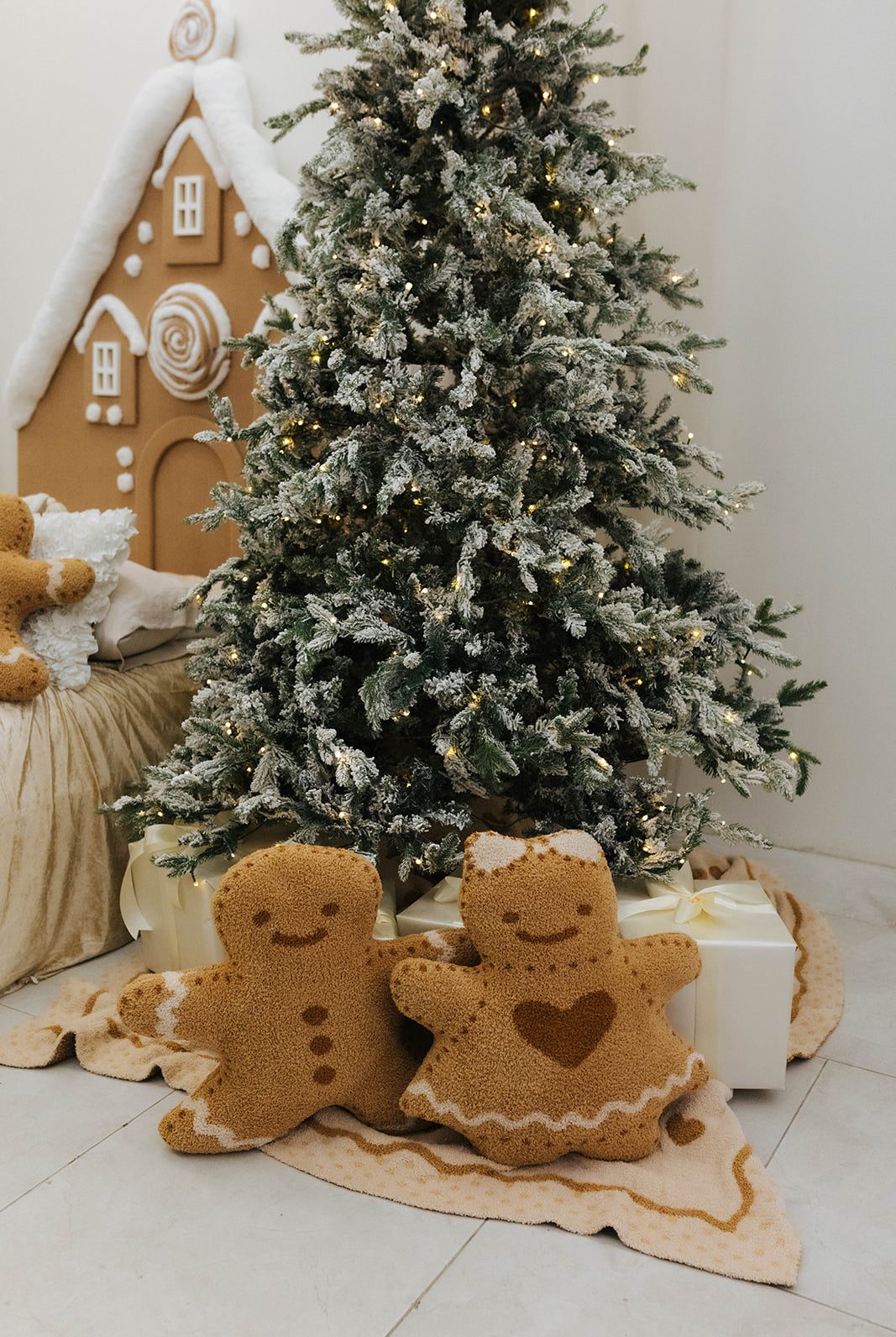 Decorative gingerbread figures in front of a Christmas tree with lights.