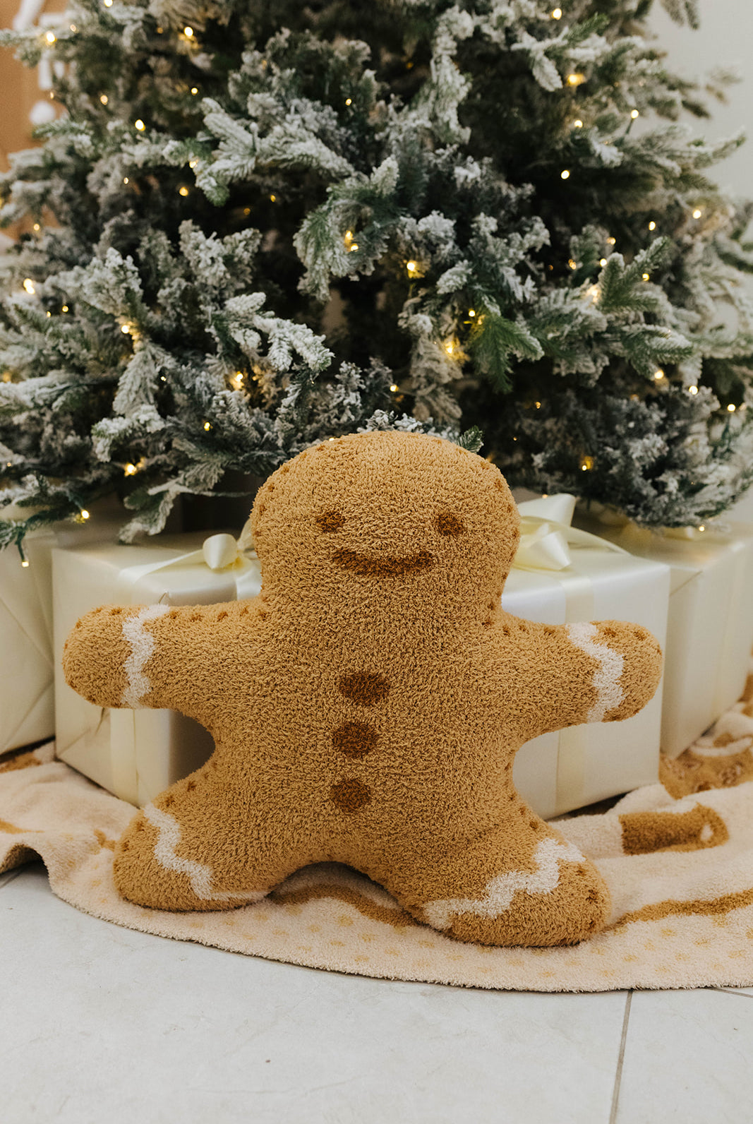 Gingerbread man decoration in front of a Christmas tree with lights.