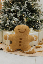 Gingerbread man decoration in front of a Christmas tree with lights.