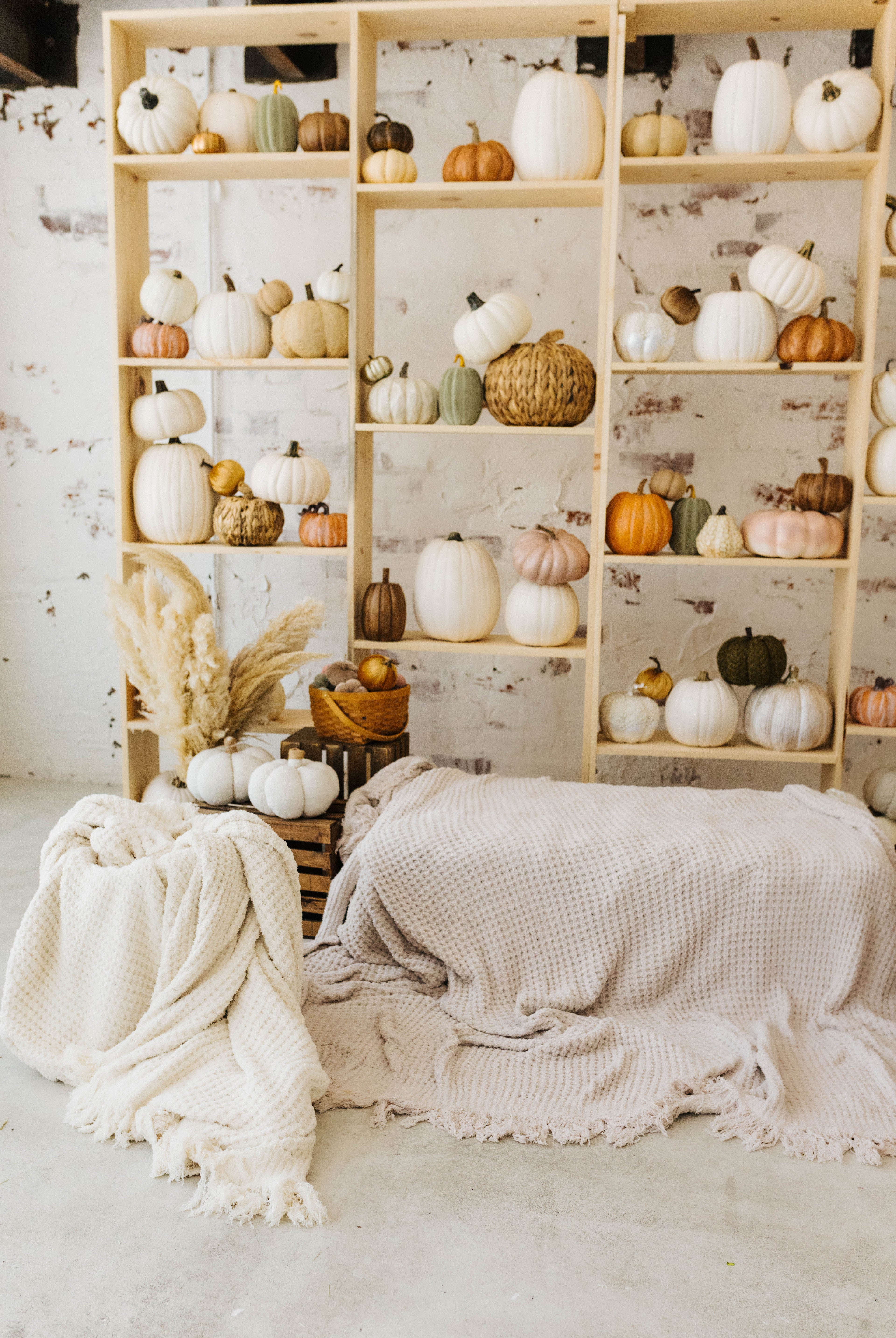 sand waffle blanket sitting in the basket neatly and cream waffle blanket laying on the hay with pumpkin decorations in the background