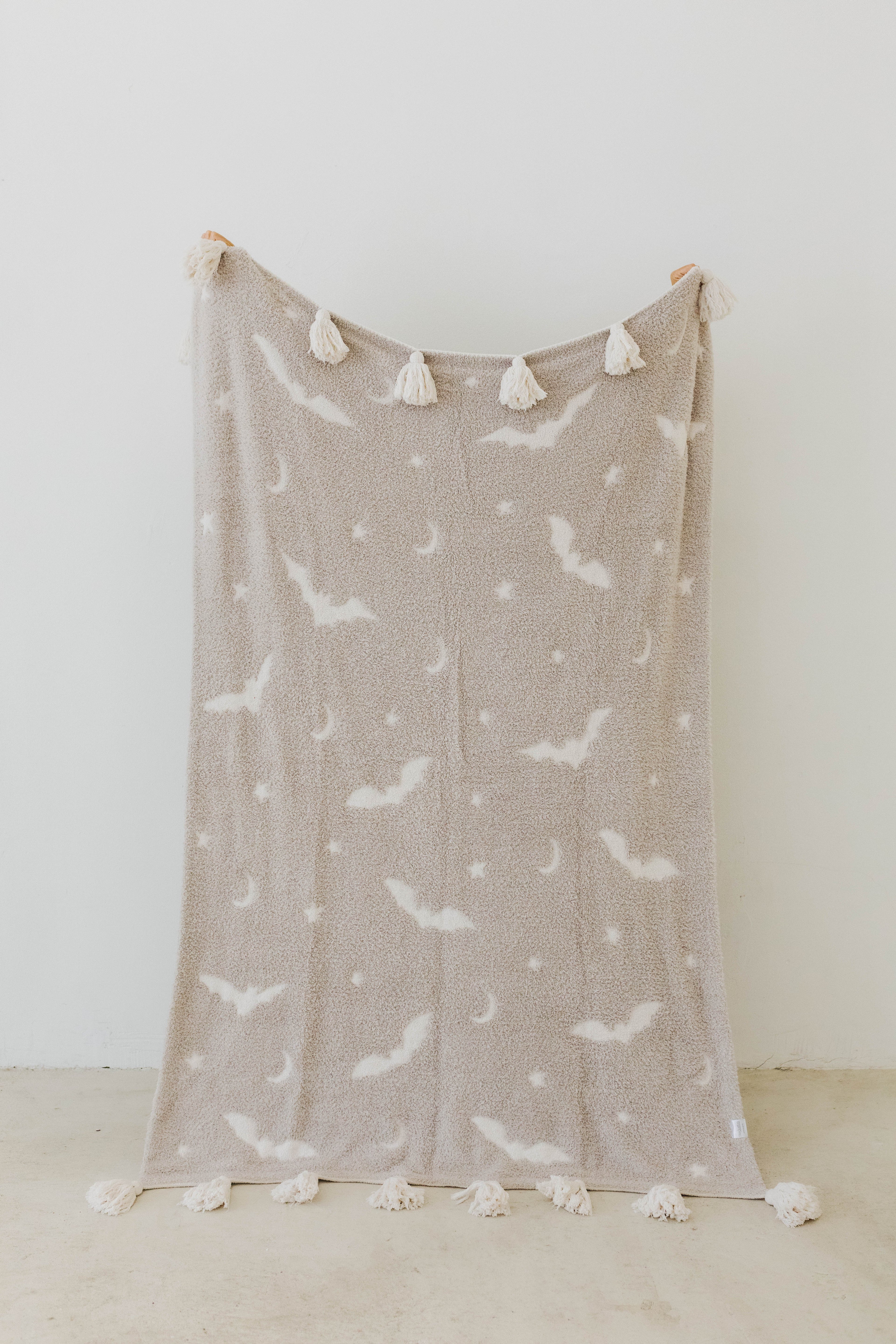 one side of bat tassel blanket - grey with white bats, moons, and stars